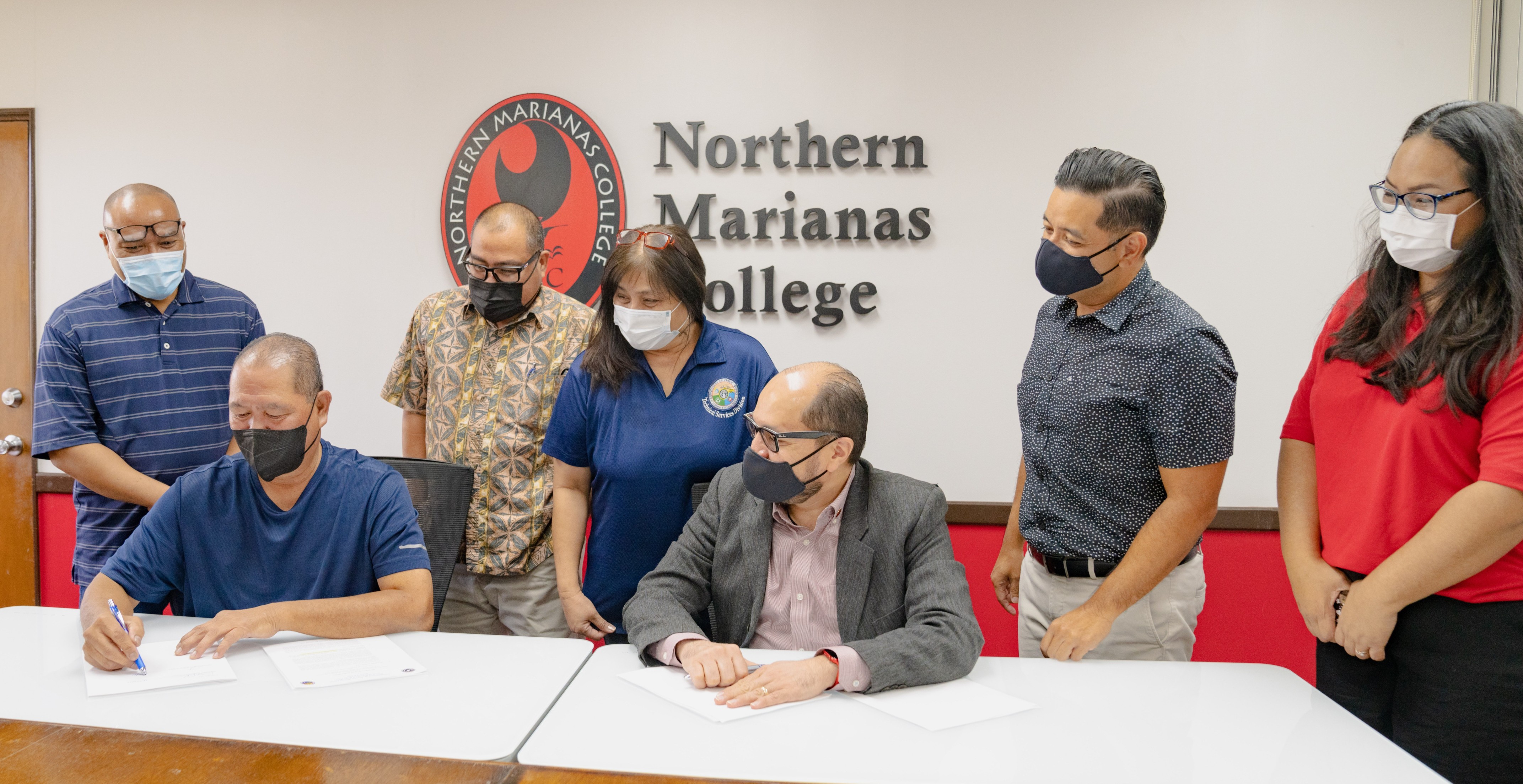 Northern Marianas College has signed an agreement with the Department of Public Works to establish a federally funded on-the-job training and social support program.  In the picture are Department of Public Works Secretary James Ada, second left, signing the MOA as NMC President Galvin S. Deleon Guerrero, Vice President for Administration and Advancement Frankie Eliptico, second right, DPW and NMC staff look on Tuesday in the NMC administration conference room.