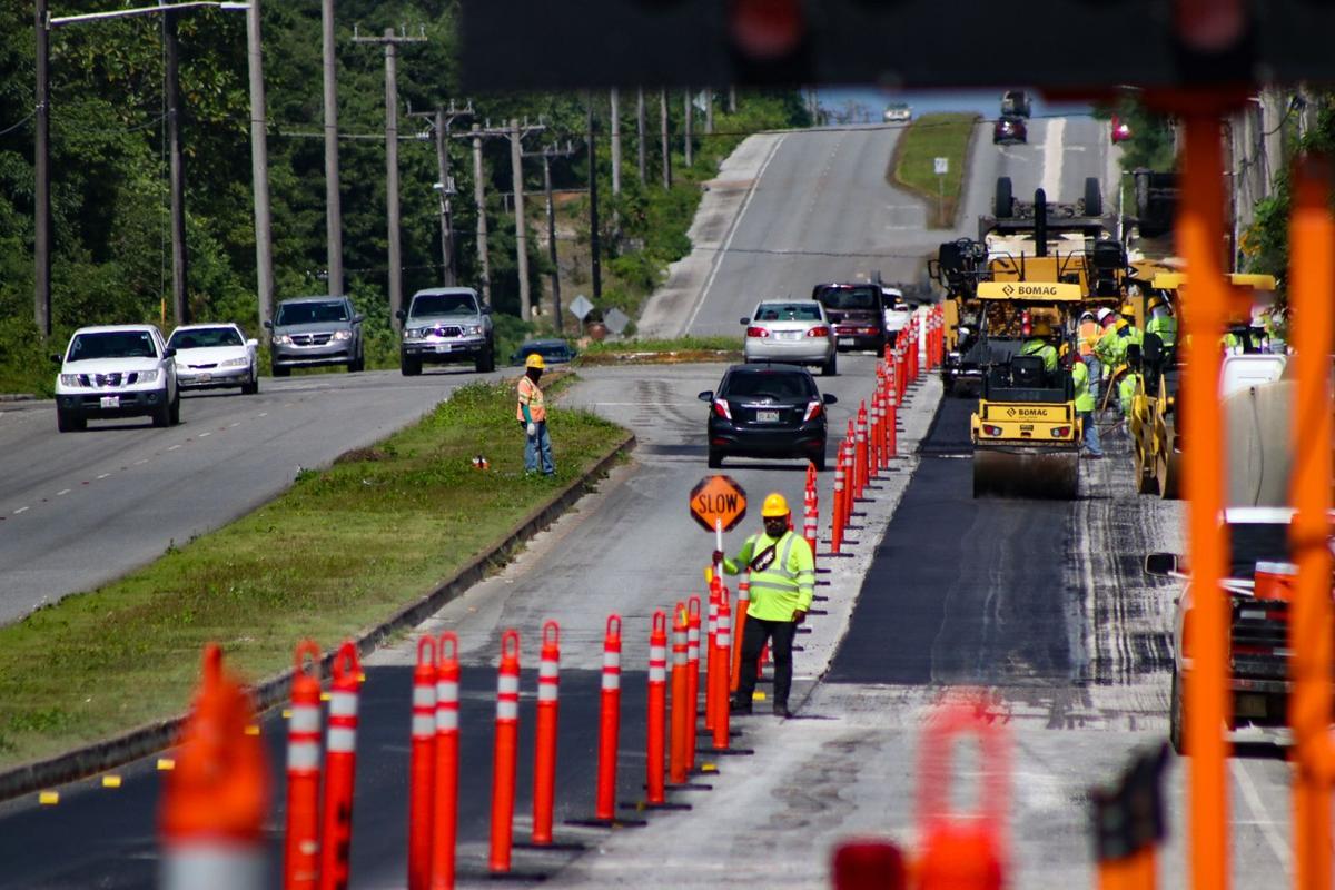 Construction crewmembers from Hawaiian Rock Products pave a section of the roadway Tuesday on Marine Corps Drive, heading north toward Andersen Air Force Base.