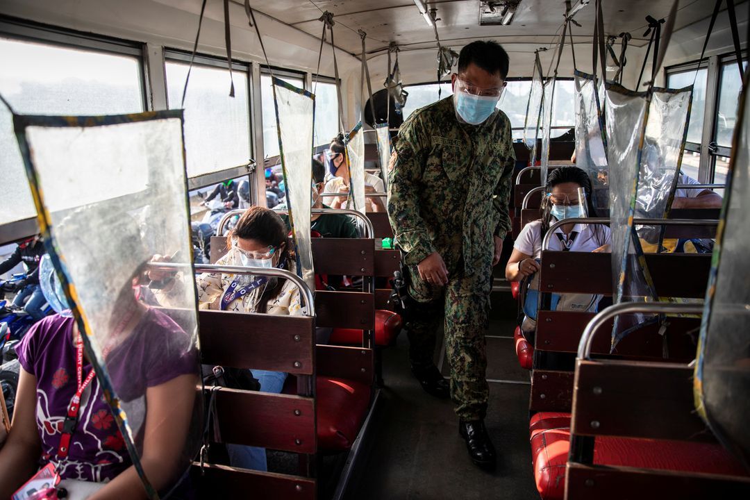 A policeman inspects a bus passing through a checkpoint on the first day of a two-week lockdown to prevent the spread of the highly infectious coronavirus Delta variant, in Quezon City, Metro Manila on Aug. 6, 2021.