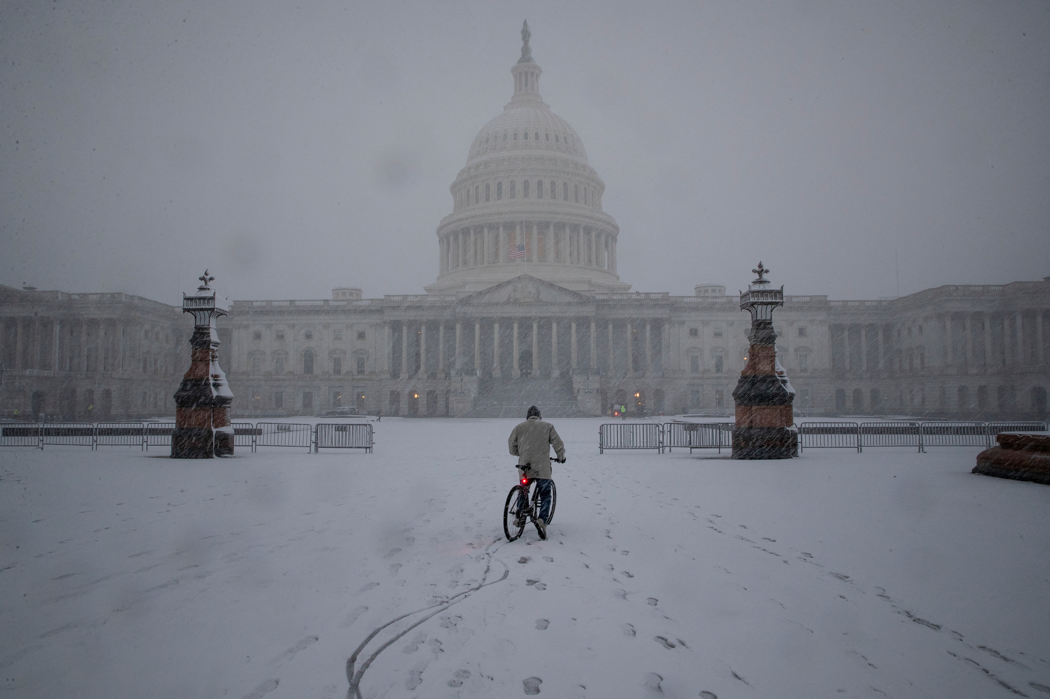 A bicyclist rides along the East Front Plaza during a snow storm on Capitol Hill in Washington, D.C., Jan. 3, 2022.