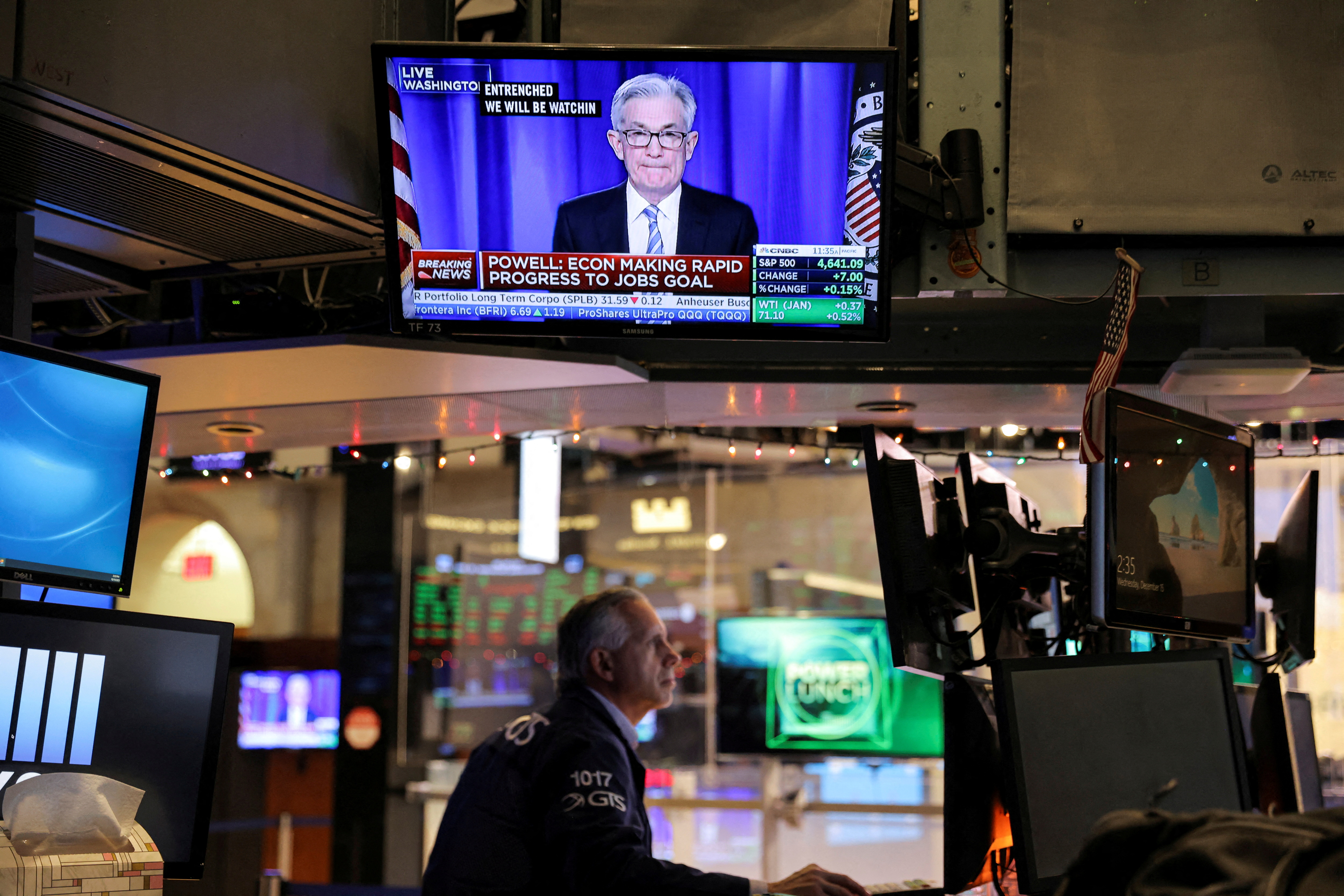 Federal Reserve Chair Jerome Powell is seen delivering remarks on a screen as a trader works on the trading floor at the New York Stock Exchange in Manhattan, New York City, Dec. 15, 2021.