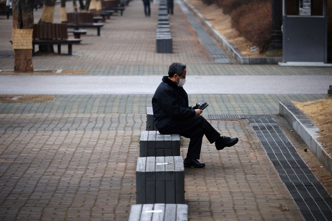 A man wearing a mask to prevent contracting the coronavirus disease rests at an empty park in Seoul, South Korea, Jan. 25, 2022.