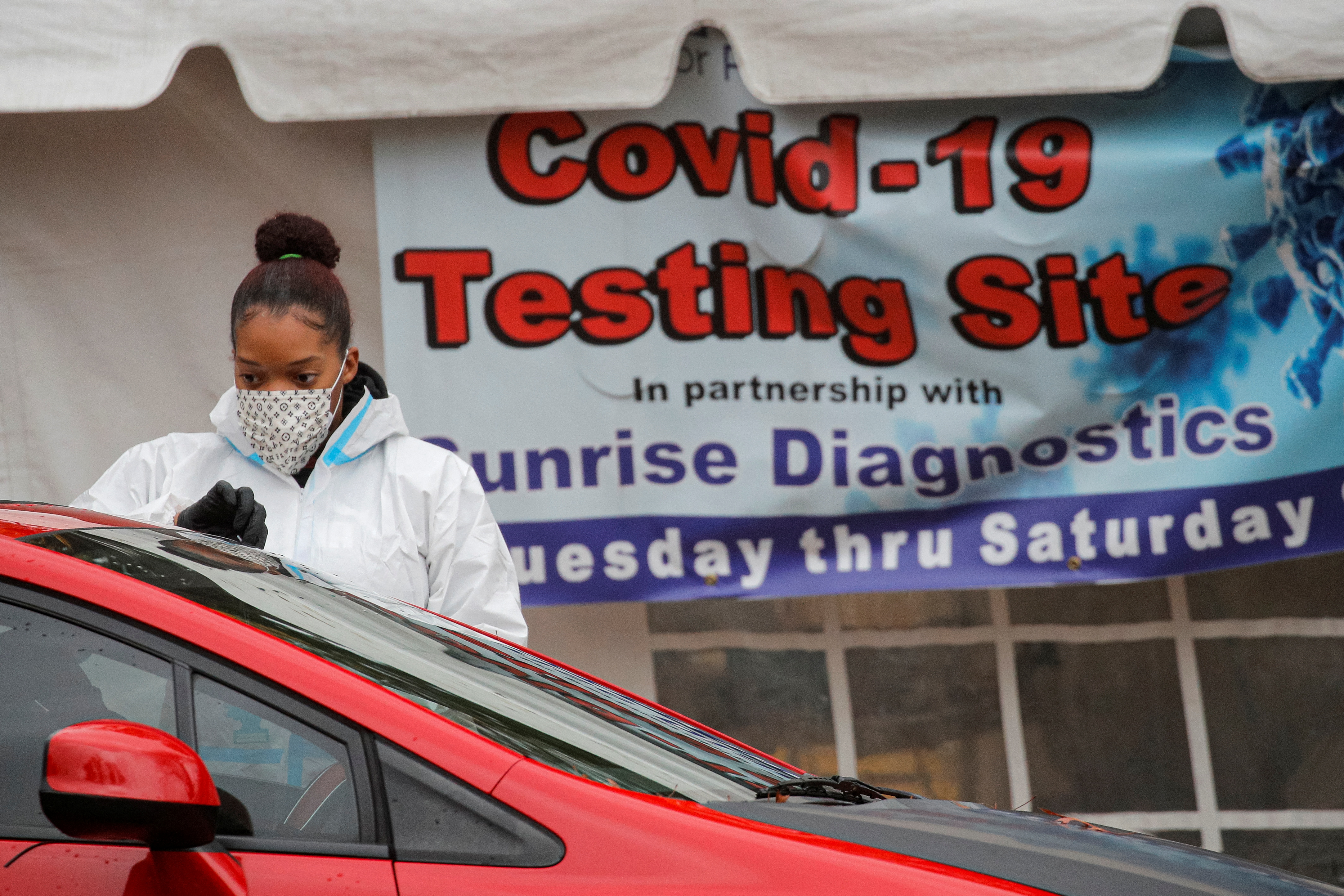 A healthcare worker takes a swab from a person sitting in a car at a drive-thru Covid-19 test center in Newark, New Jersey, Nov. 12, 2020.