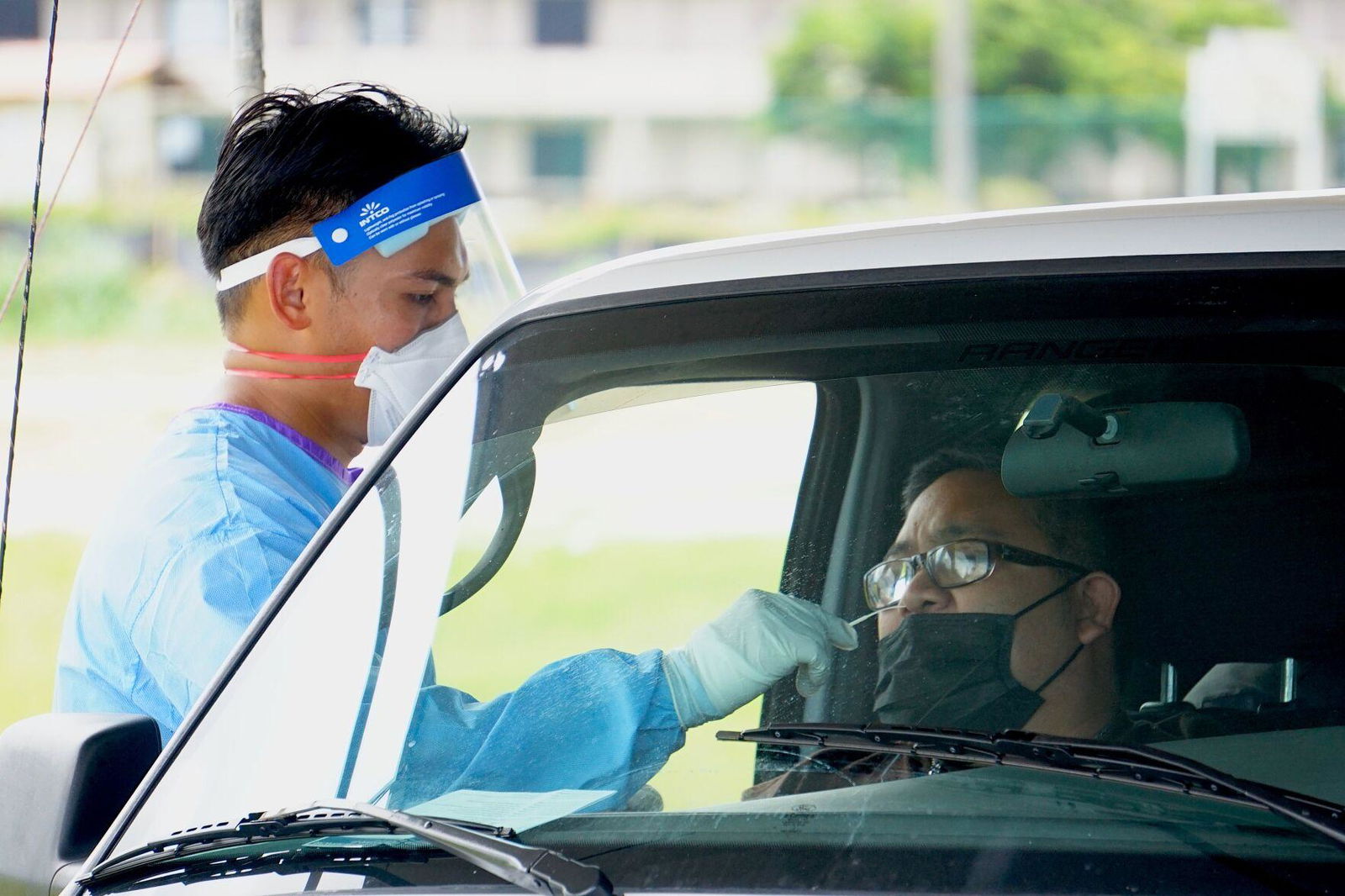 A nurse performs a polymerase chain reaction, or PCR, test by swabbing during a drive-thru testing clinic at the old carnival grounds in Tiyan, Guam on Aug. 28, 2021.The Guam Daily Post file photo