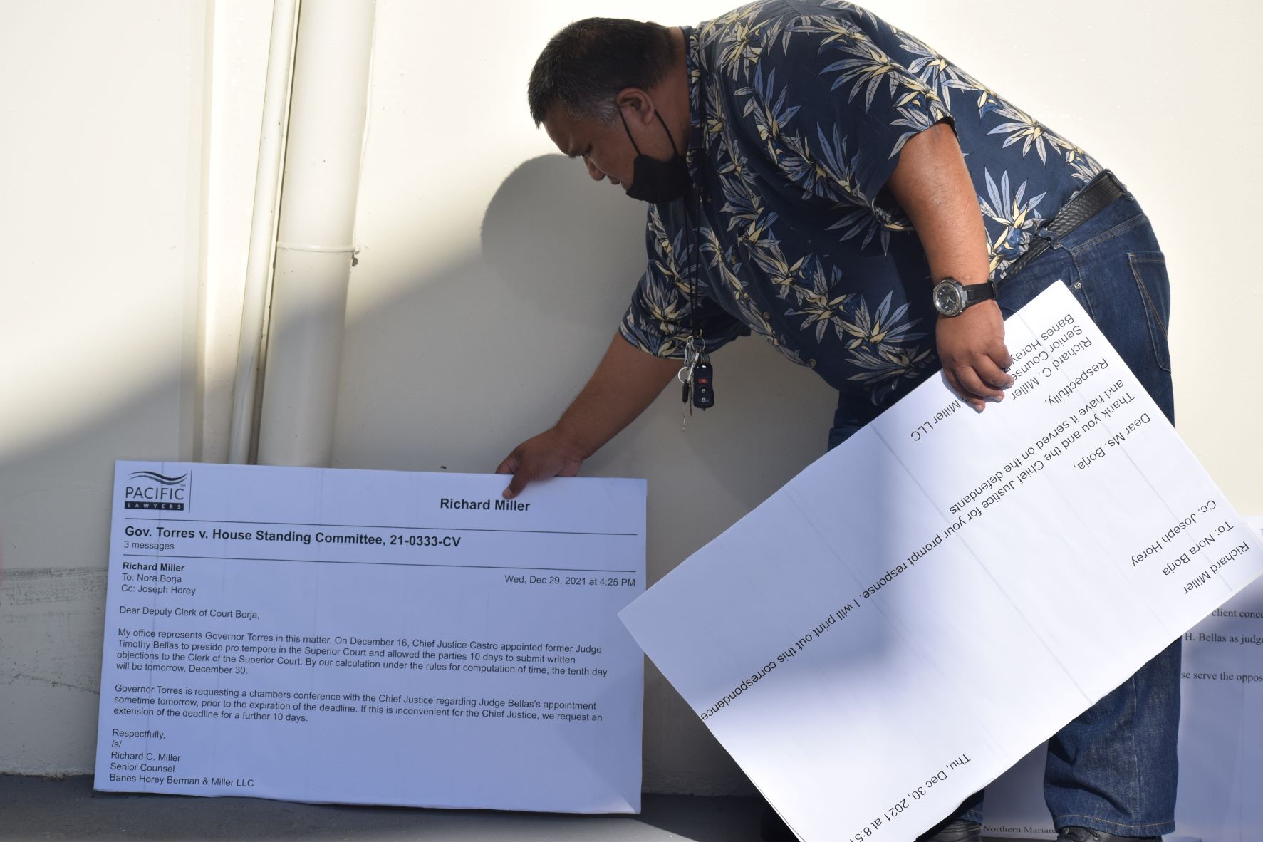 Legislative Bureau librarian Simion Lisua puts up a large printed copy of an email against the exterior wall of the legislative building on Wednesday.