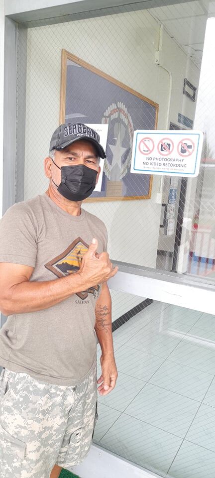 Military veteran and vlogger Fabian Indalecio flashes the shaka sign outside the administration building on Thursday. The sign on the glass door reads, “No Photography, No Video Recording Without Express Written Permission.”