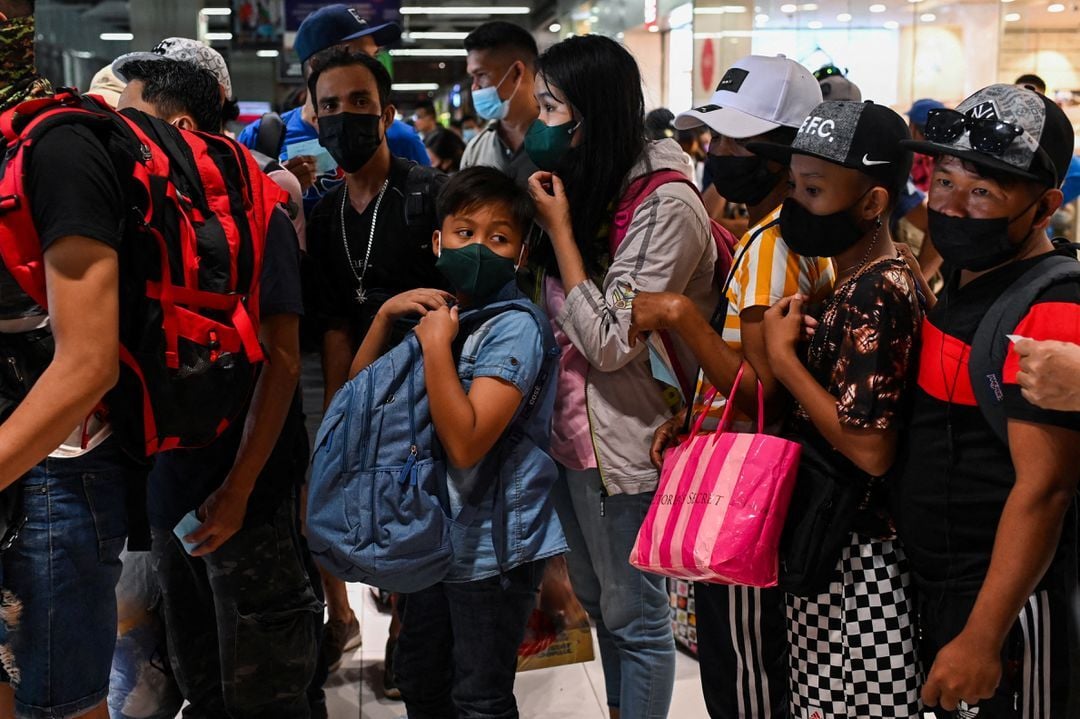 People wearing face masks as protection against the coronavirus disease wait to ride a bus going to provinces, a day before New Year's Eve, at a bus terminal in Parañaque City, Metro Manila on Dec. 30, 2021.
