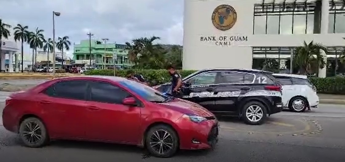 This image from a video shows two police officers approaching the driver’s side of a Toyota sedan that was blocking traffic on the southbound lane of Beach Road in downtown Garapan Friday afternoon.