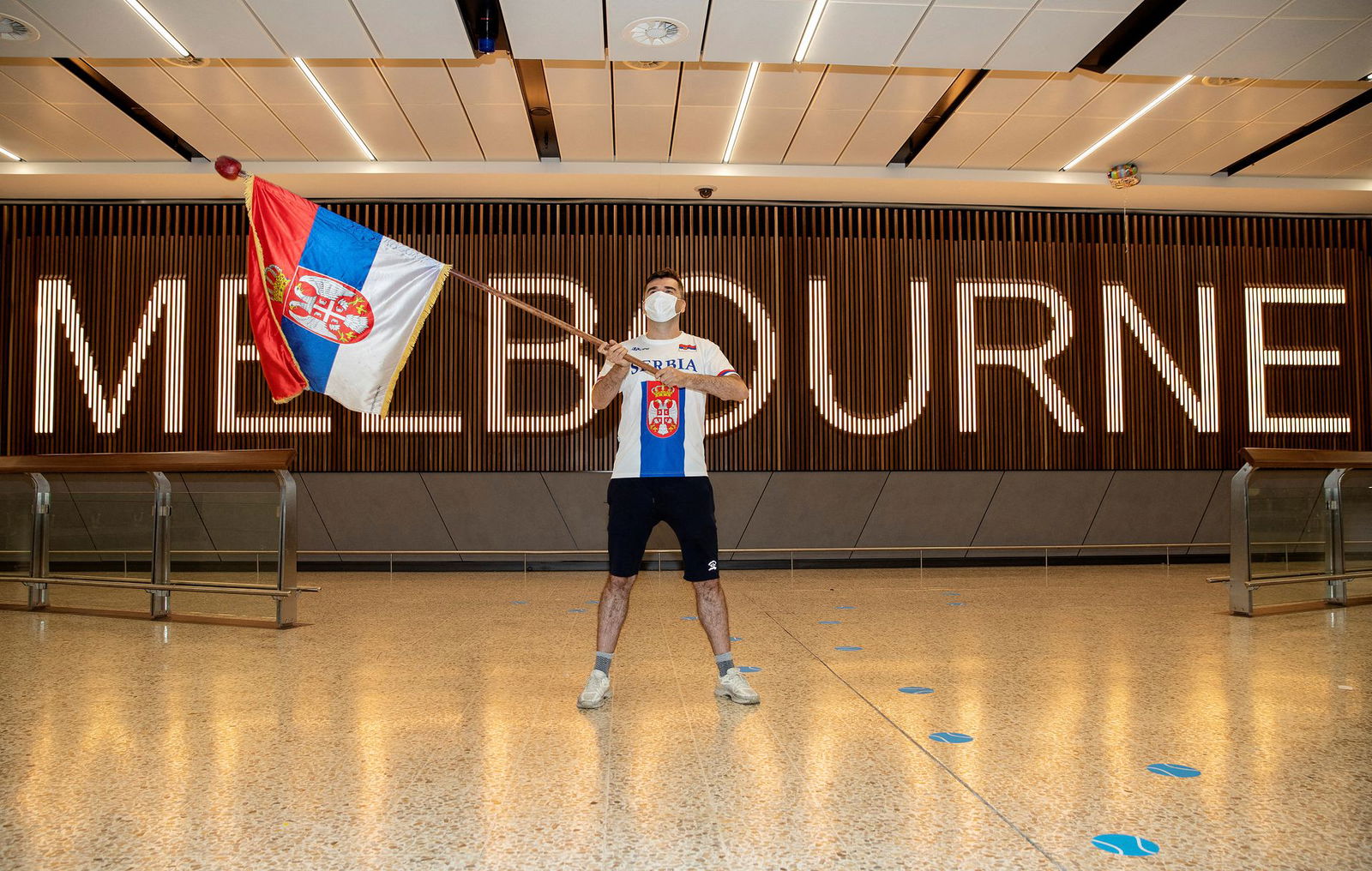 A fan of Serbian tennis player Novak Djokovic is seen waving a Serbian flag while awaiting the arrival of Djokovic at Melbourne International Airport, in Melbourne, Australia, Jan. 6, 2022.
