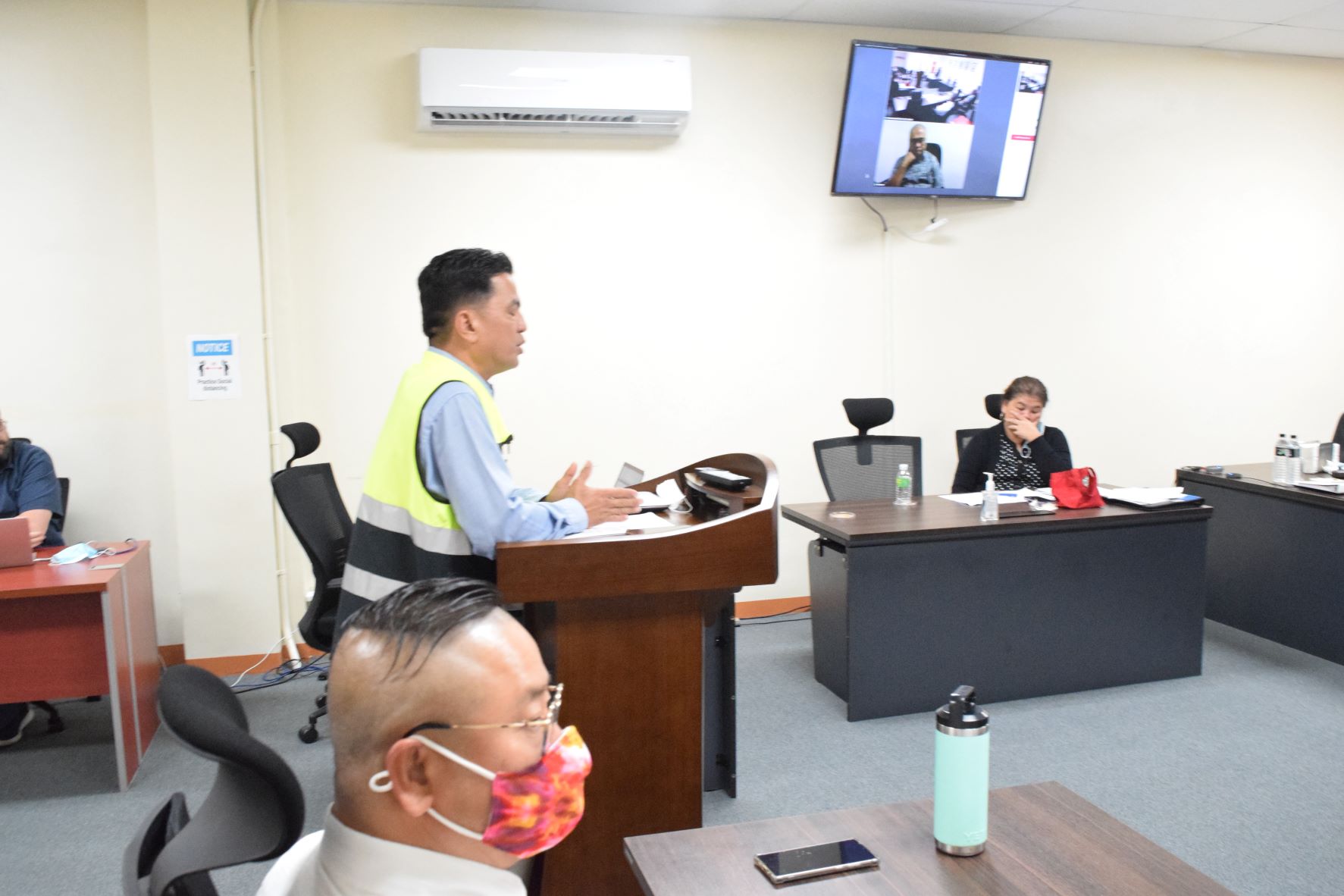 Imperial Pacific International Chief Executive Officer Ray Yumul, gestures as he speaks before the  Commonwealth Casino Commission during its monthly meeting in Gualo Rai on Thursday. Also in the photo are Commission Executive Director Andrew Yeom, left foreground; Commission Chairman Edward C. Deleon Guerrero, seen on a monitor; and Executive Assistant to the Commission Ruth Ann P. Sakisat.