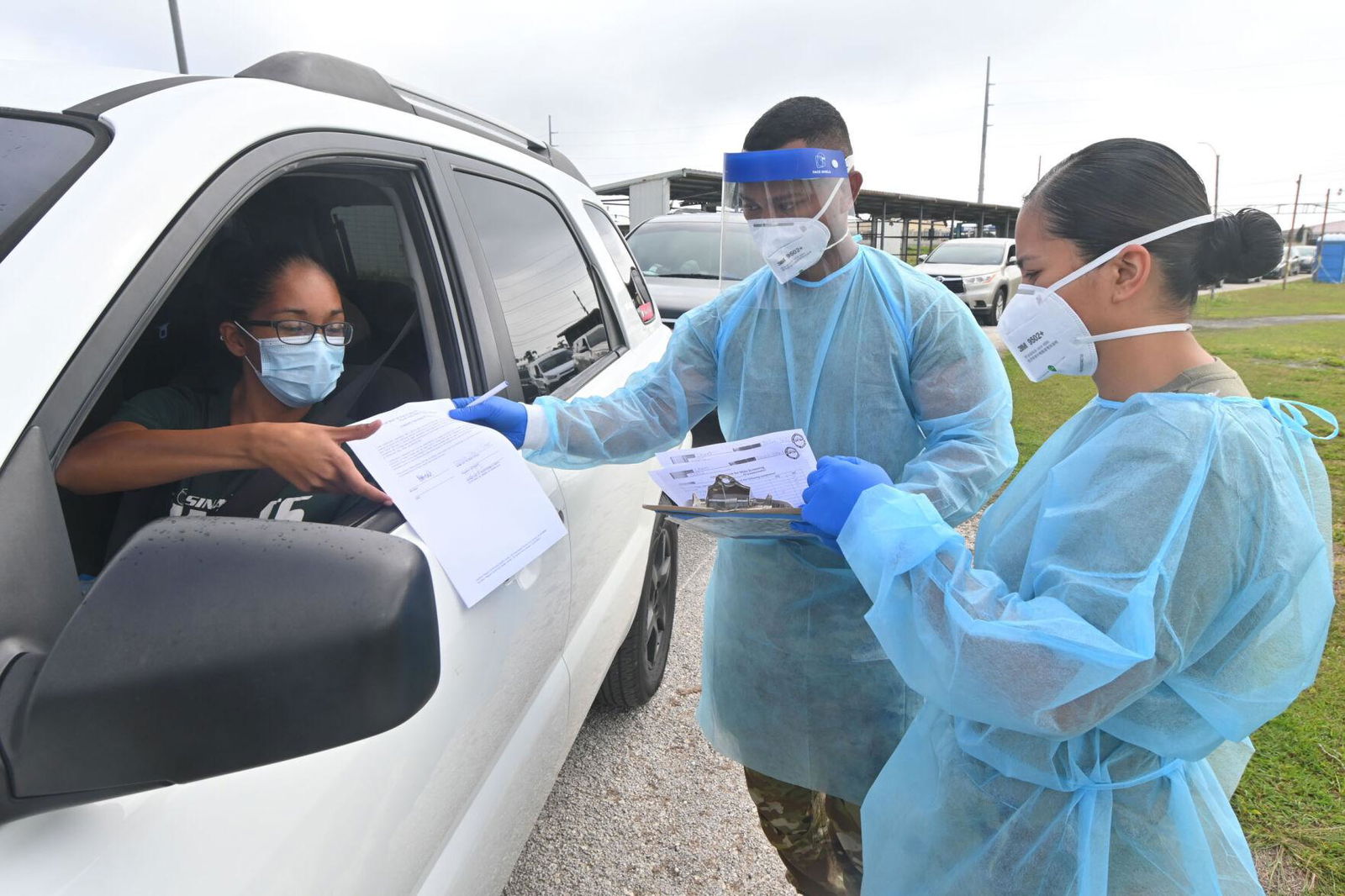 Joslyn Chinel, from Agana Heights, completes screening paperwork with Guam National Guard members Spc. Samuel Figir and Spc. Francine Daga during a drive-thru Covid-19 testing Monday at Tiyan.