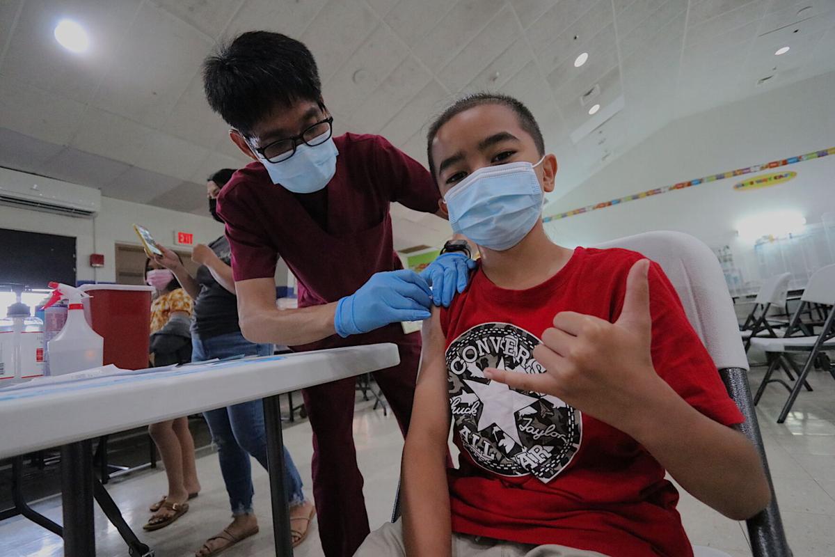 Ten-year-old BraydenJames Flores who is a fourth-grade student, displays the shaka sign as he completes is first jab of the Pfizer Covid-19 vaccine during an outreach clinic at Guam’s Machananao Elementary School on Wednesday. 