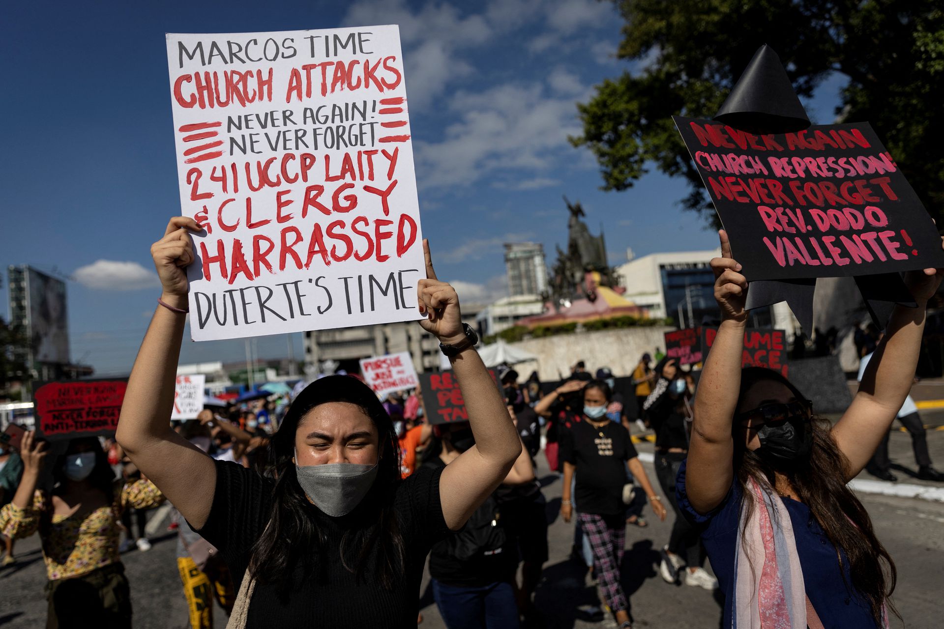 Filipinos raise placards during a rally marking the anniversary of the 1986's People Power Revolution that overthrew the late dictator Ferdinand Marcos, near the EDSA People Power monument in Quezon City, Metro Manila on Feb. 25, 2022.