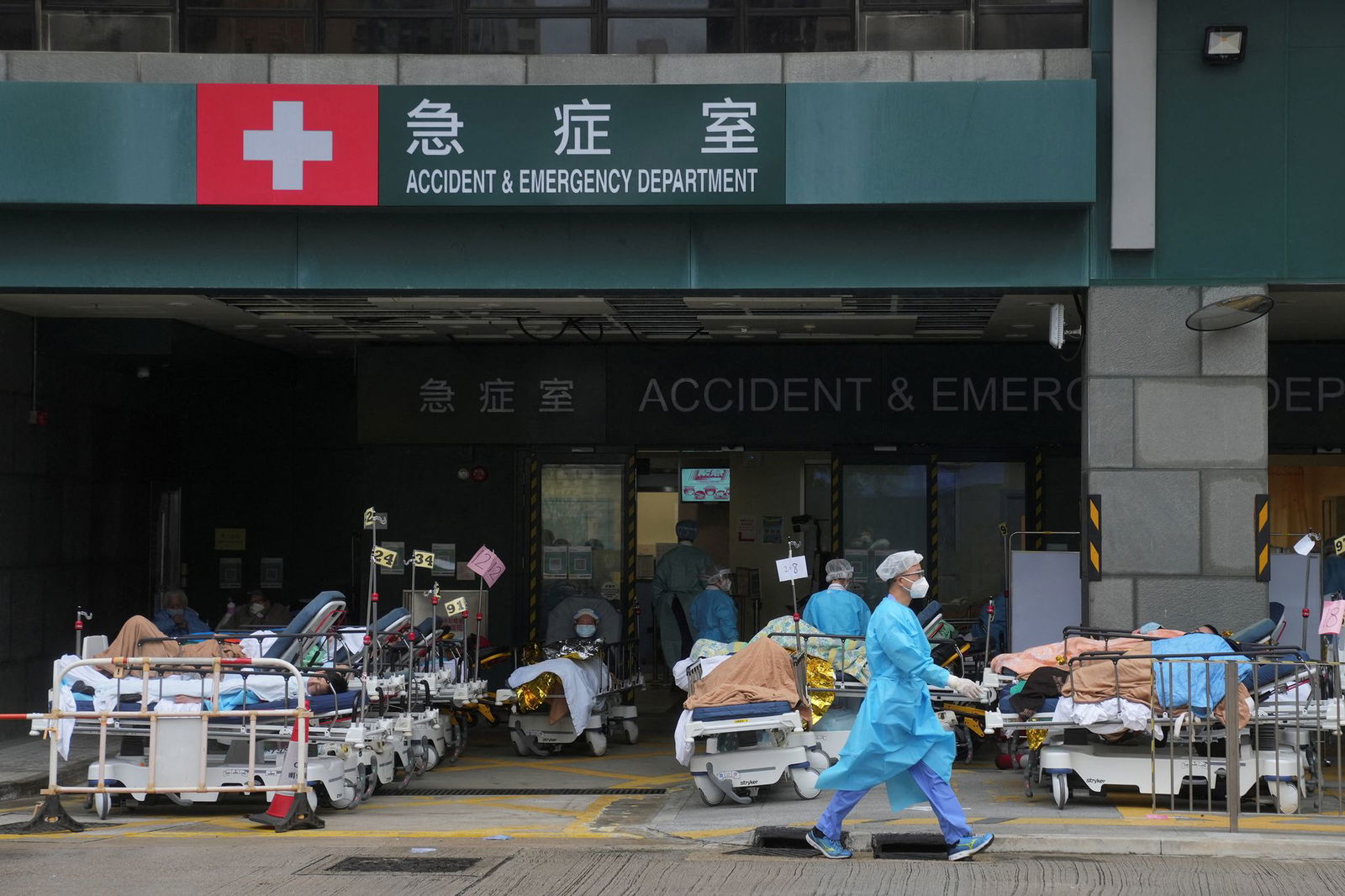 Medical personnel wearing personal protective equipment work among patients lying in beds in a makeshift treatment area outside a hospital, following the coronavirus disease outbreak in Hong Kong on Feb. 17, 2022.