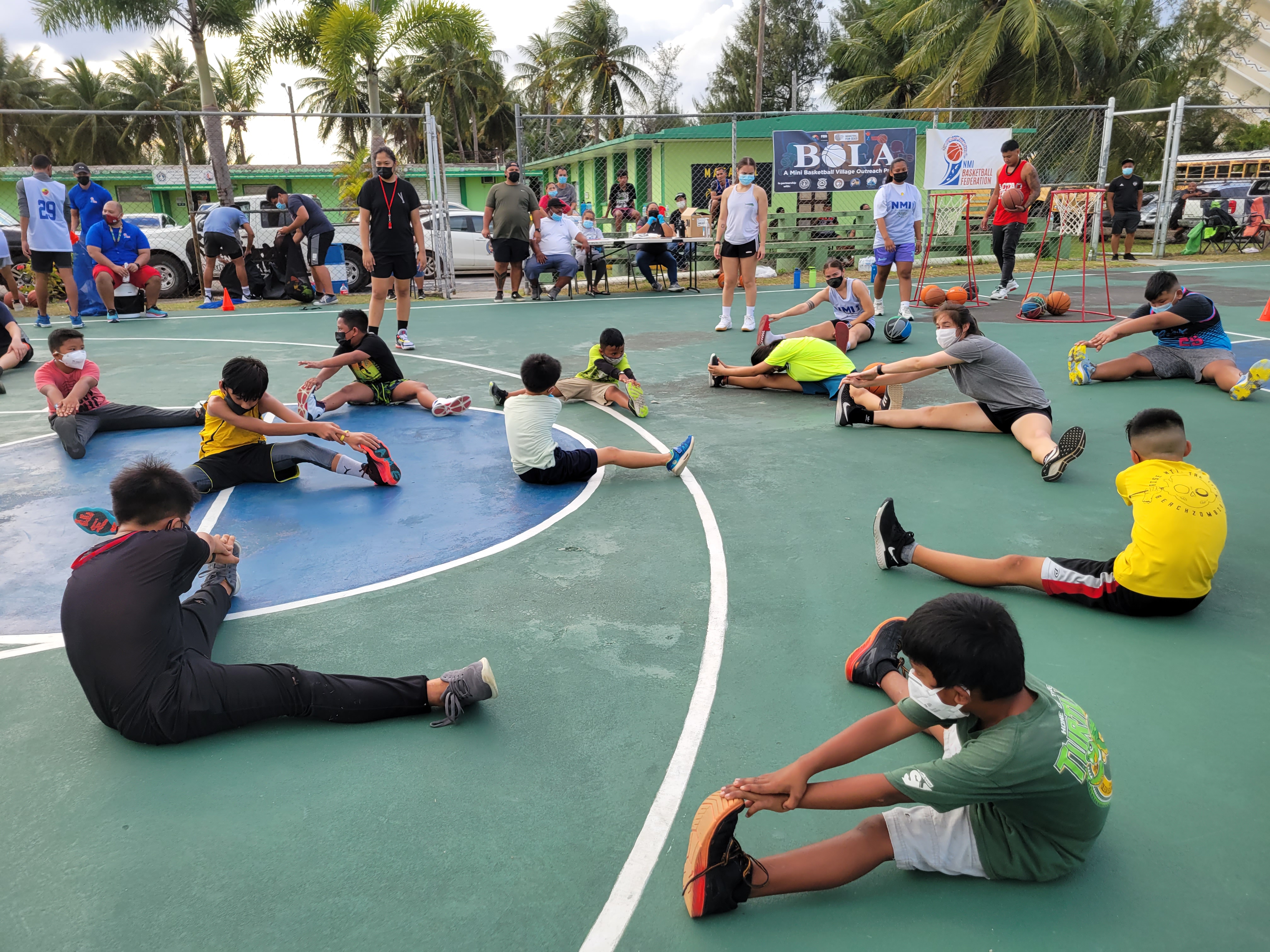 Participants in the second “Bola” session participate in a stretching drill at the Garapan Basketball Court on Jan. 29.