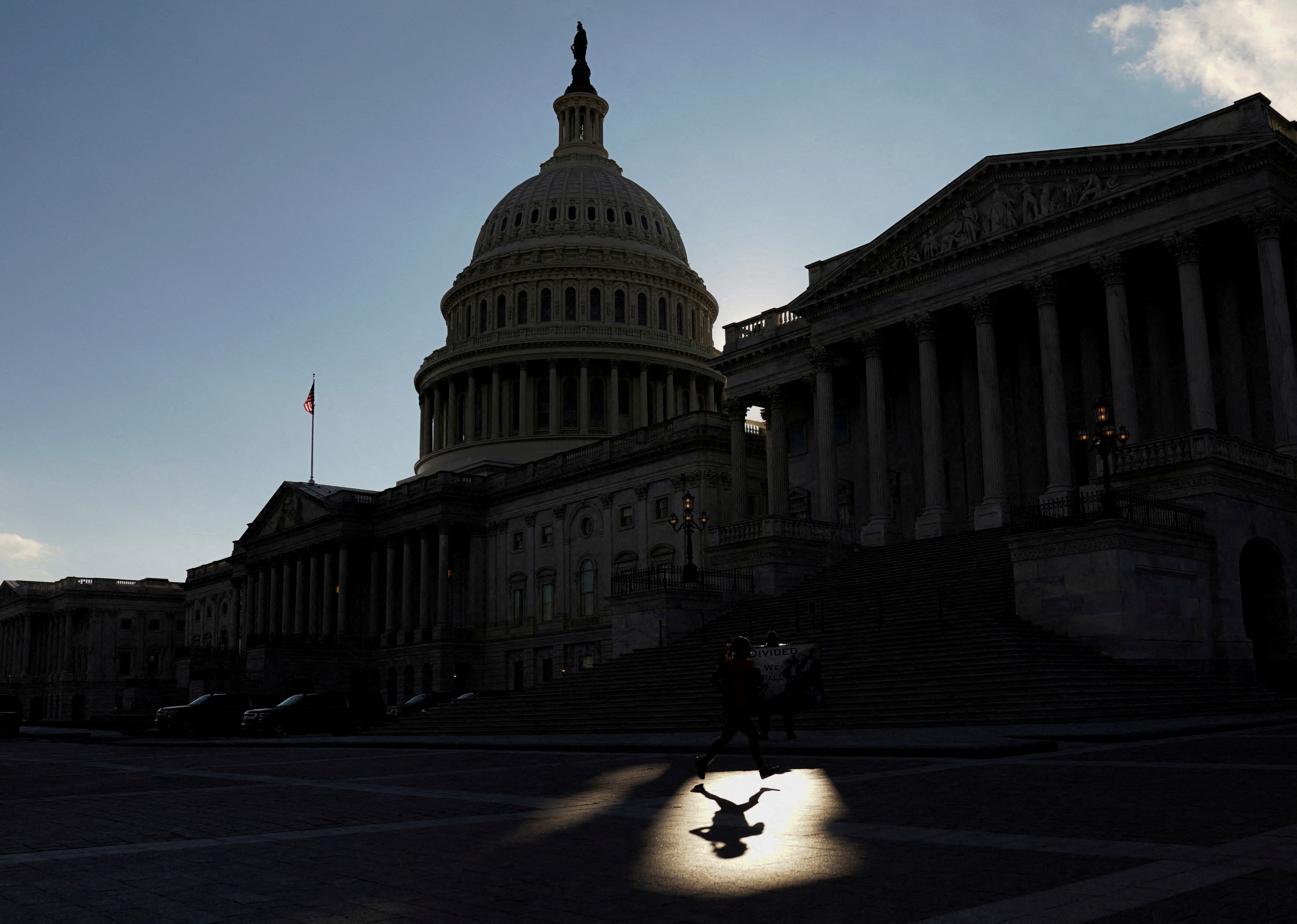 A jogger passes through a beam of sunlight in front of the U.S Capitol in Washington, D.C., Jan. 18, 2022.