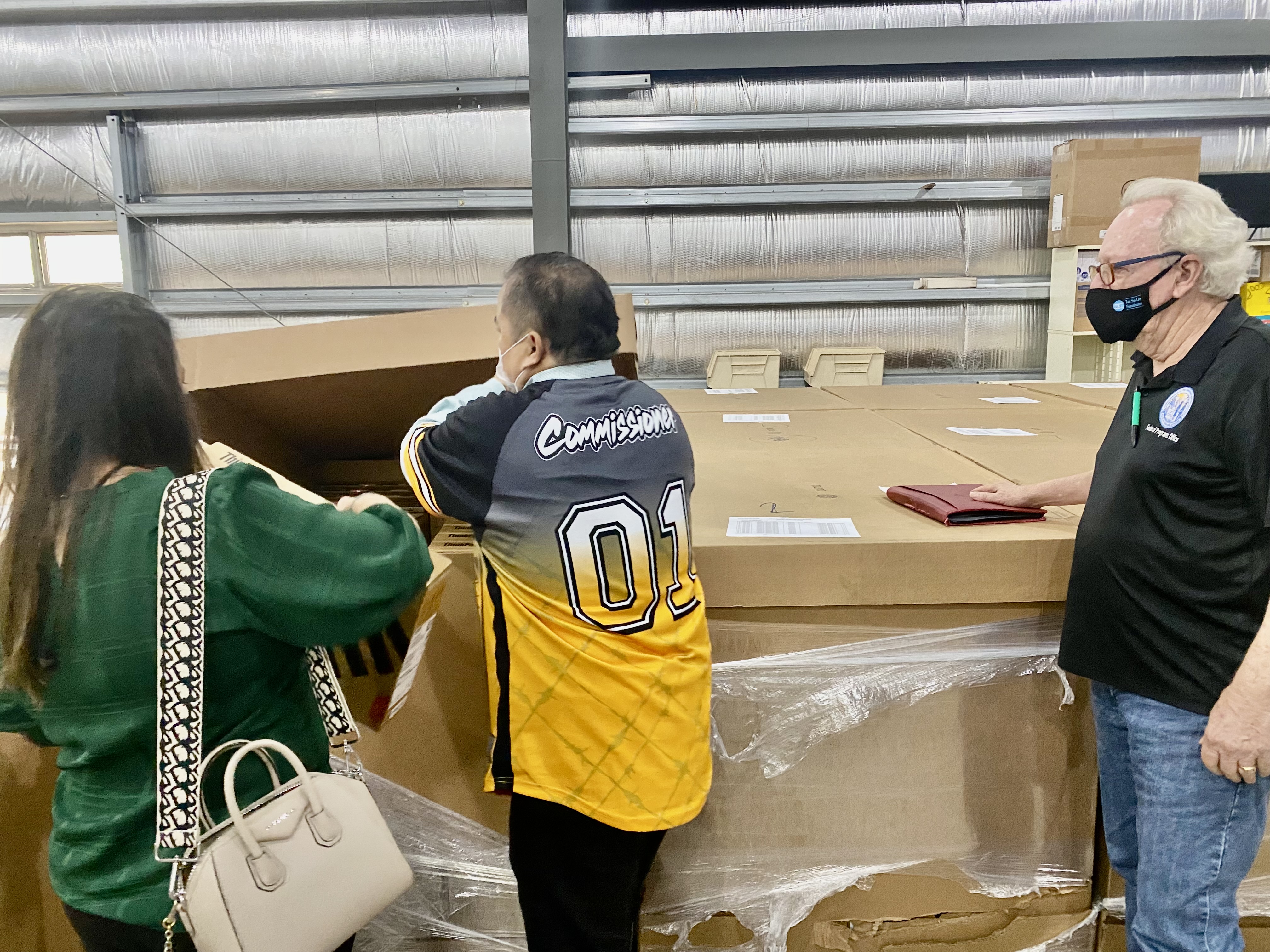 Commissioner of Education Dr. Alfred B. Ada, center, opens one of the huge crates containing newly arrived laptops while PSS-Federal Programs Officer Tim Thornburgh, right, and PSS Student Support Services Senior Director Dr. Yvonne Pangelinan look on.