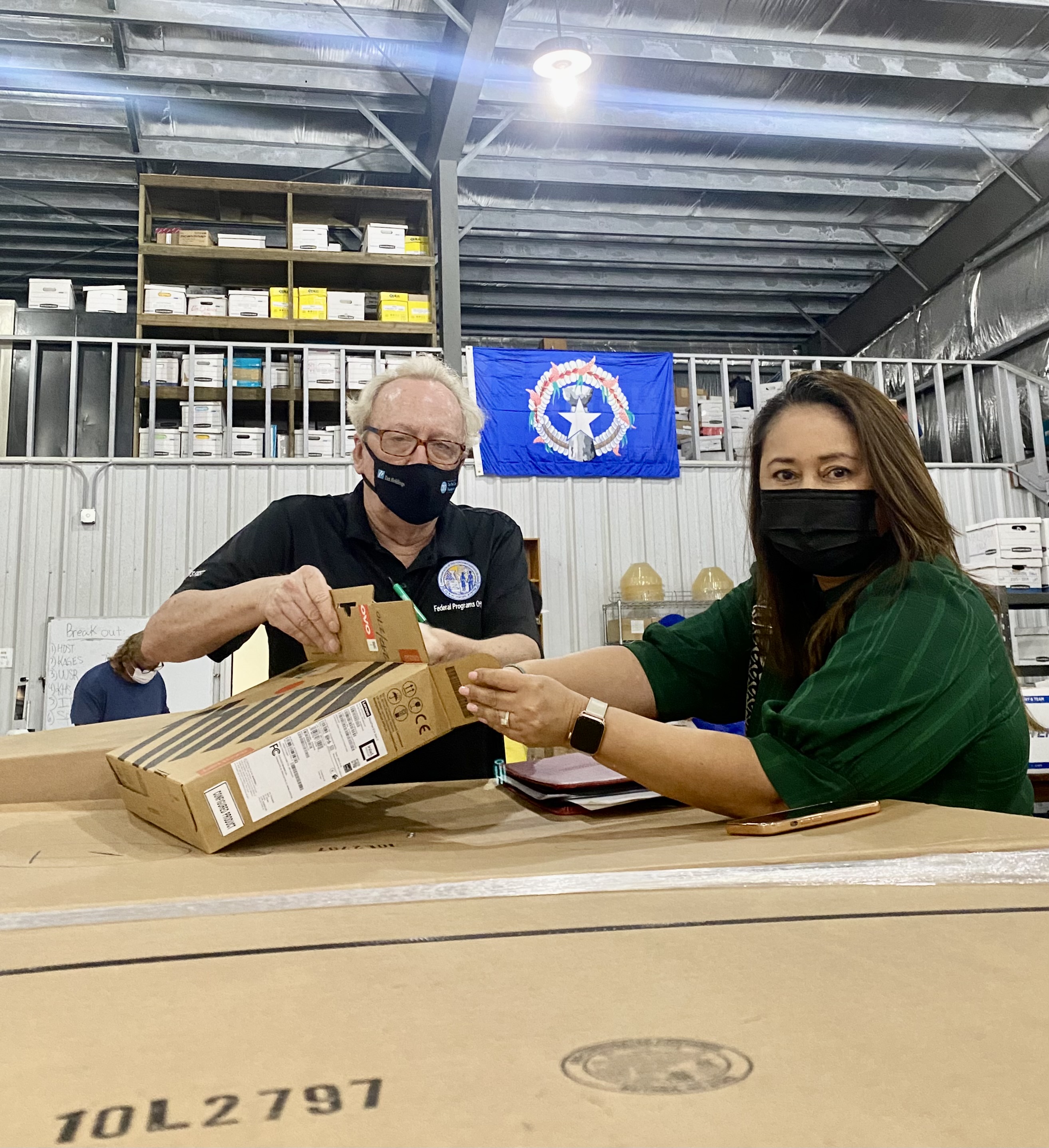 PSS Federal Programs Officer Tim Thornburgh and Student Support Services Senior Director Dr. Yvonne Pangelinan unbox one of the newly arrived laptops.