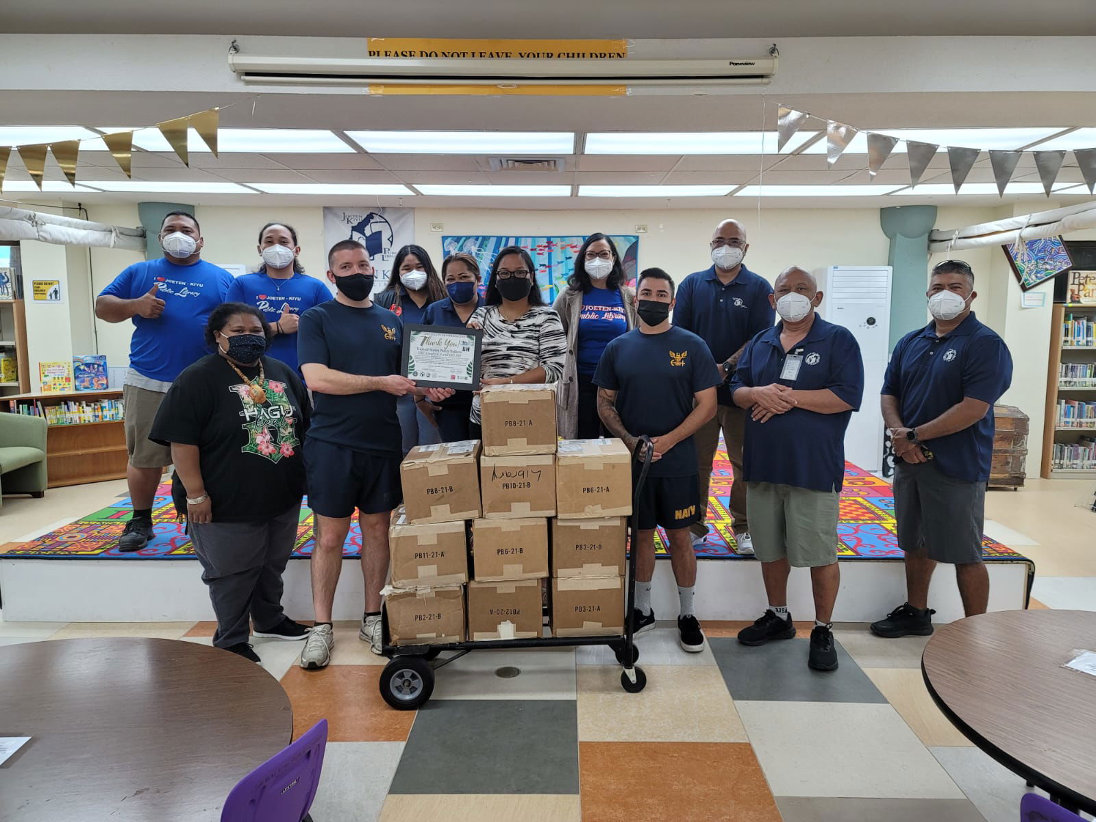 Joeten-Kiyu Public Library Director Erlinda Naputi, center, hands a plaque of appreciation to one of the sailors of USS Emory S. Land which donated 10 boxes of books on Tuesday.