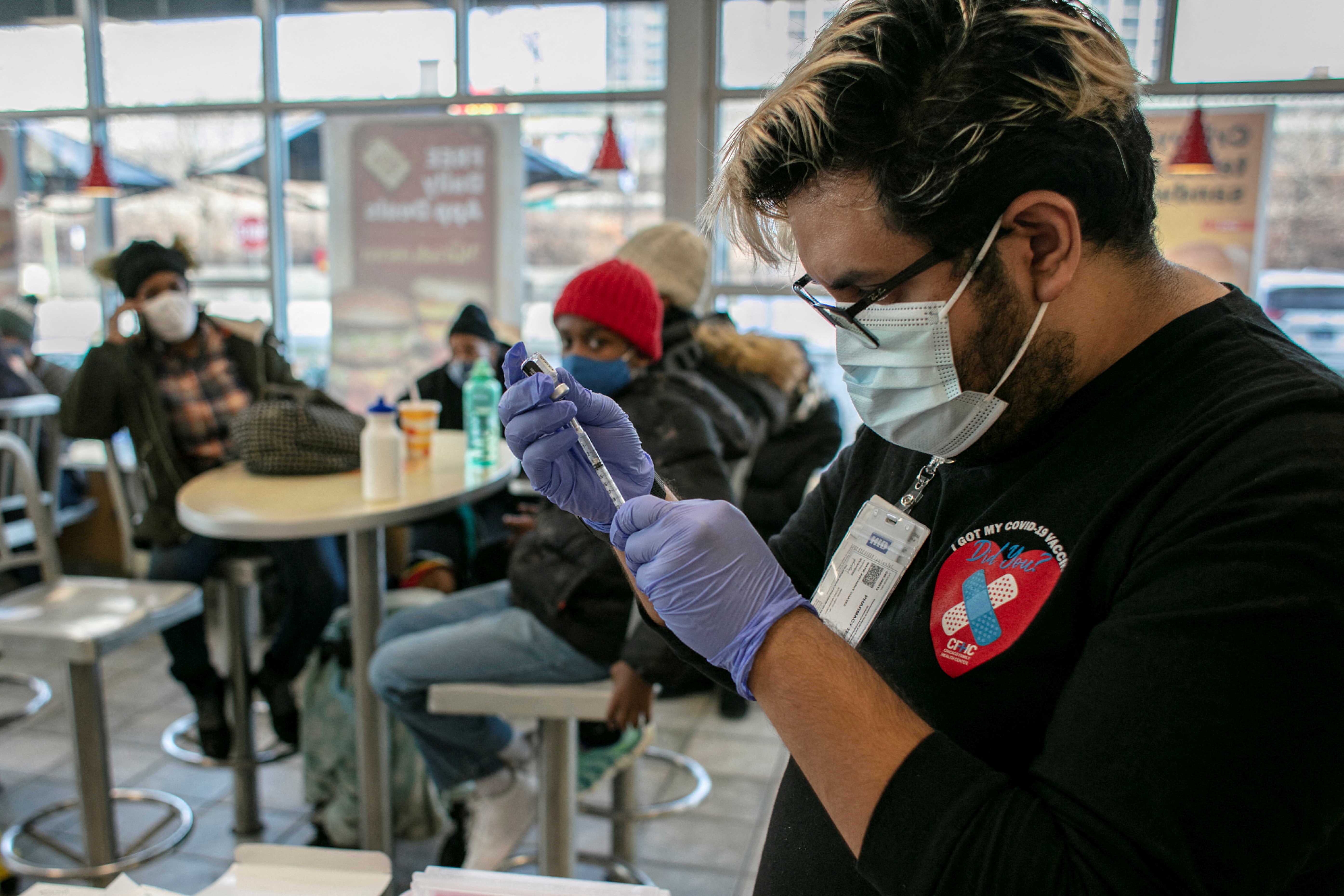 A worker from Chicago Family Health Center prepares a booster shot for the coronavirus disease at a McDonald's in Chicago, Illinois, Dec. 21, 2021.