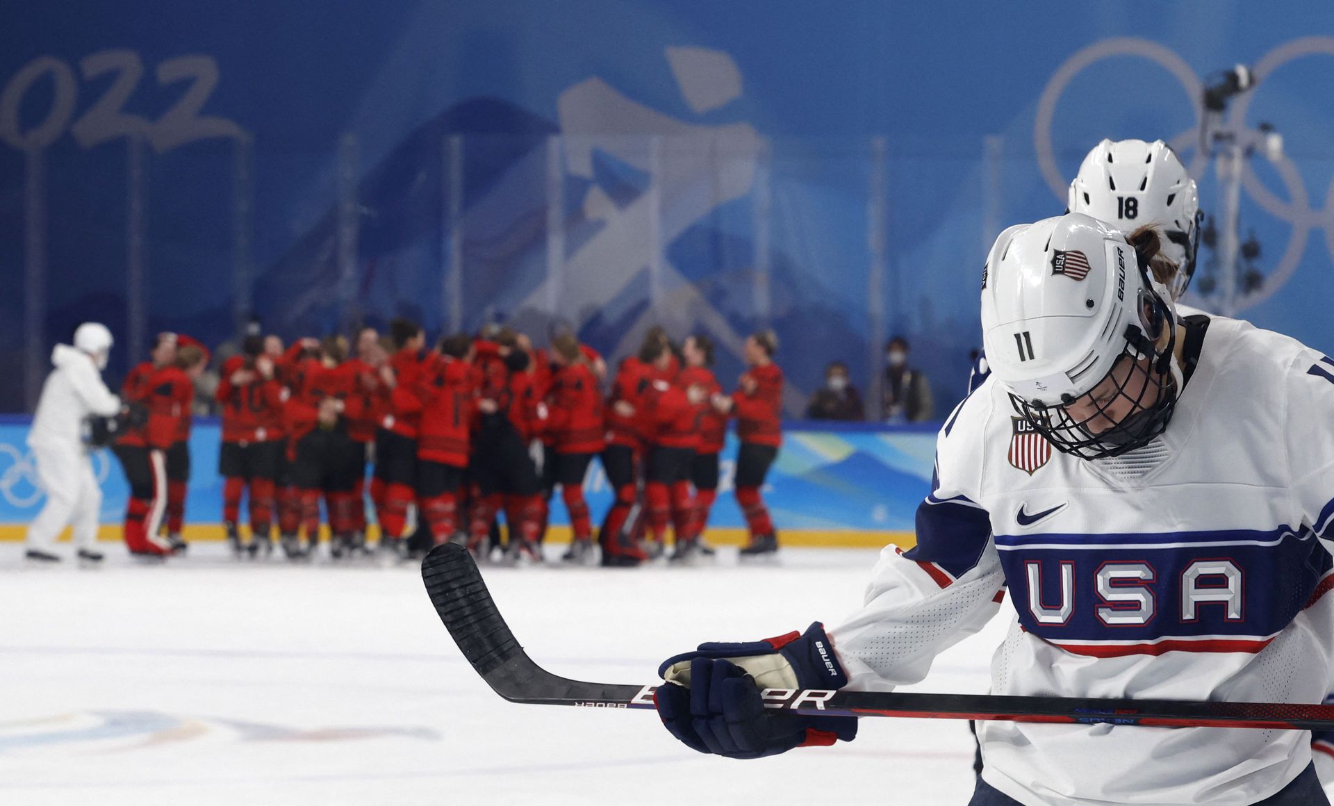 Abby Roque of the United States looks dejected as Canada players celebrate victory at the Wukesong Sports Center, Beijing, China on Feb. 17, 2022.