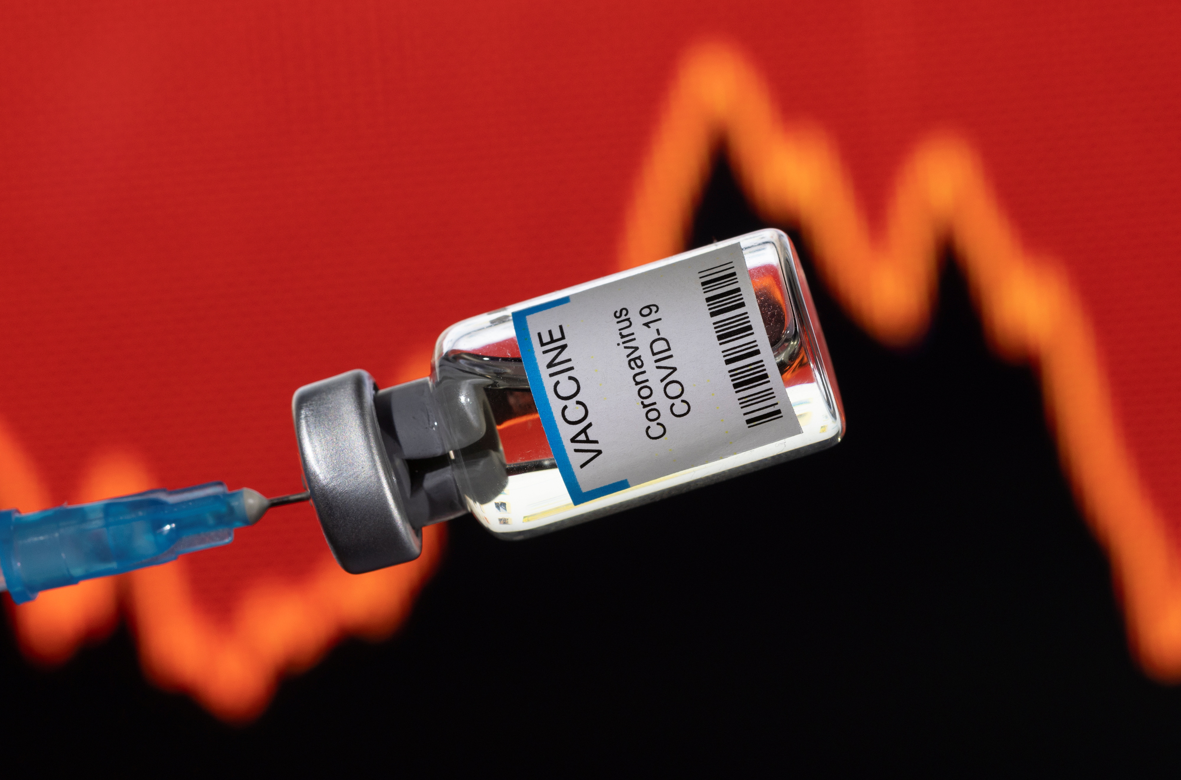 A vial labelled "VACCINE Coronavirus COVID-19" is seen in front of a stock graph in this illustration taken on Jan. 17, 2022. 