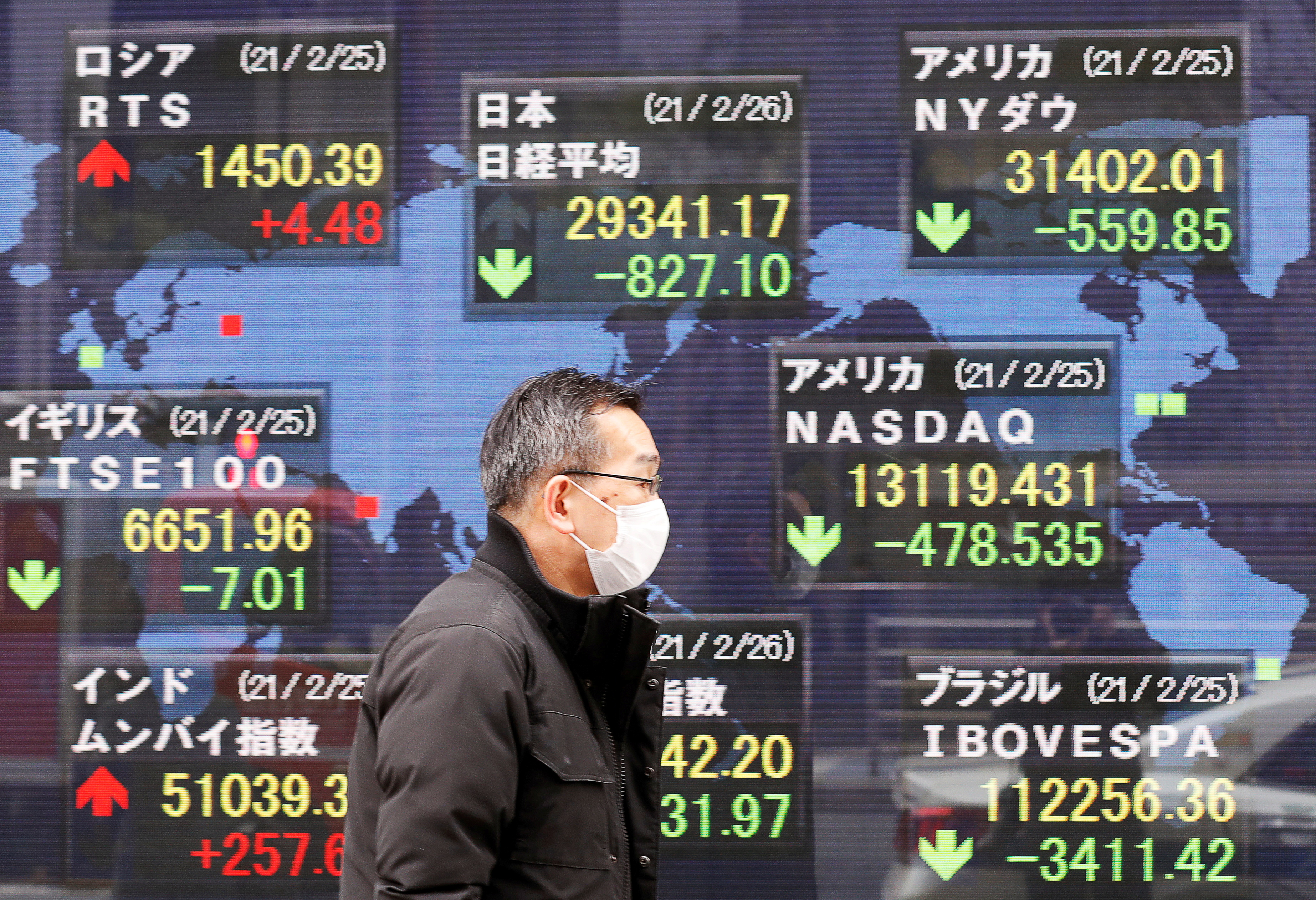 A man walks past a stock quotation board at a brokerage in Tokyo, Japan on Feb. 26, 2021.