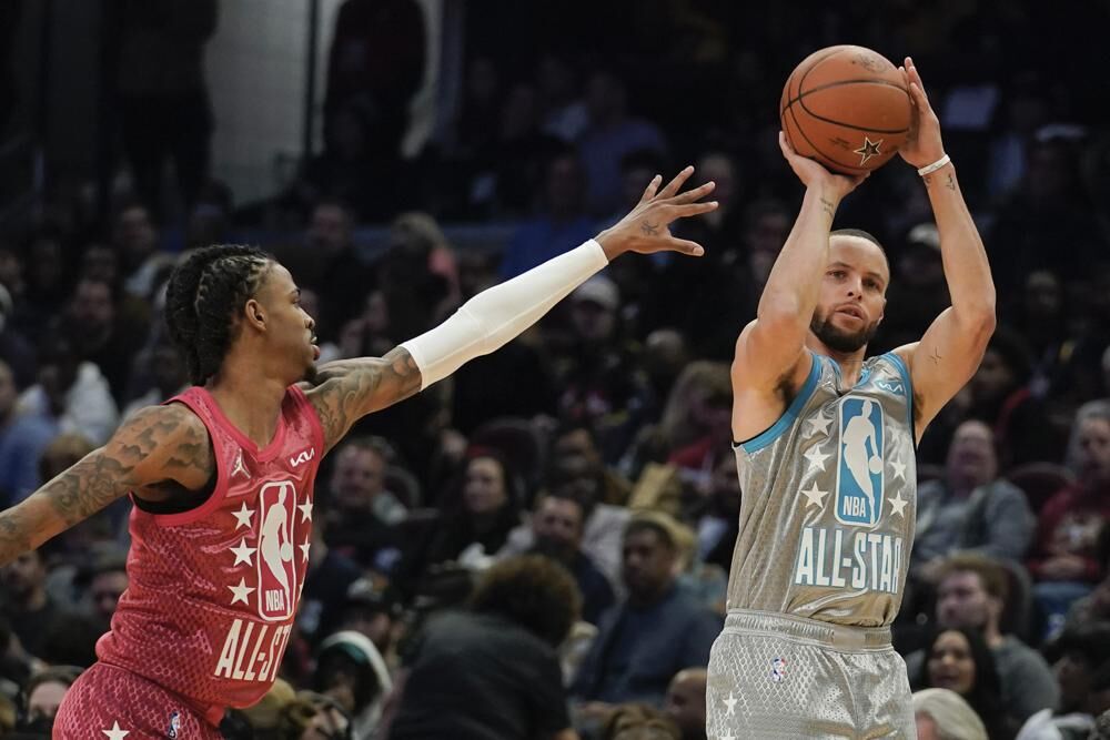 Golden State Warriors' Stephen Curry, right, shoots for three as Memphis Grizzlies' Ja Morant defends during the second half of the NBA All-Star basketball game, Sunday, in Cleveland.