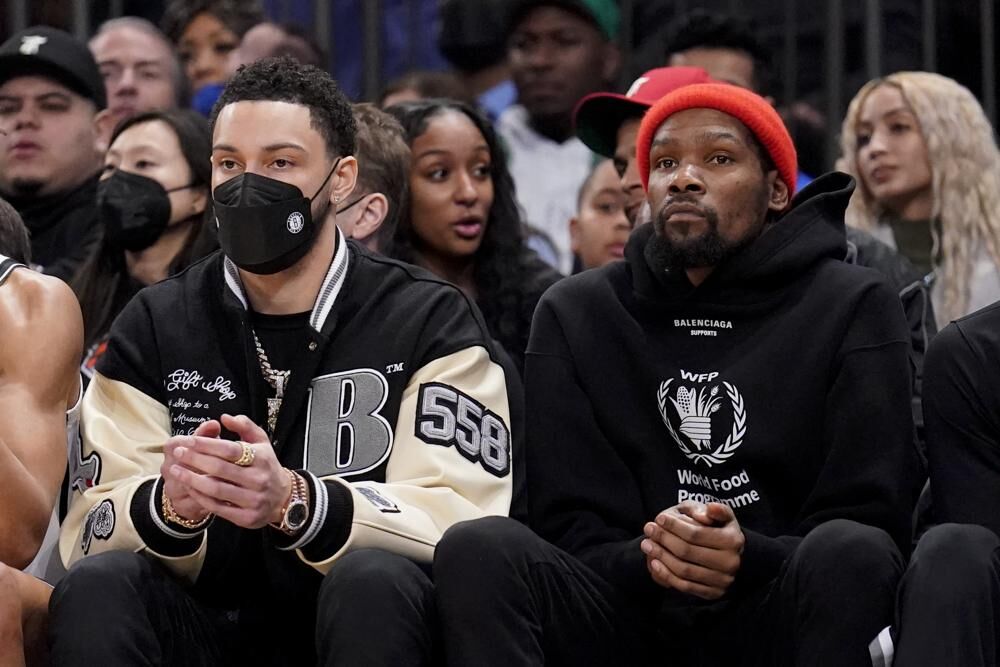 Brooklyn Nets forward Ben Simmons, left, sits with forward Kevin Durant, right, on the bench during the first half of an NBA basketball game against the New York Knicks, Feb. 16, 2022, in New York.