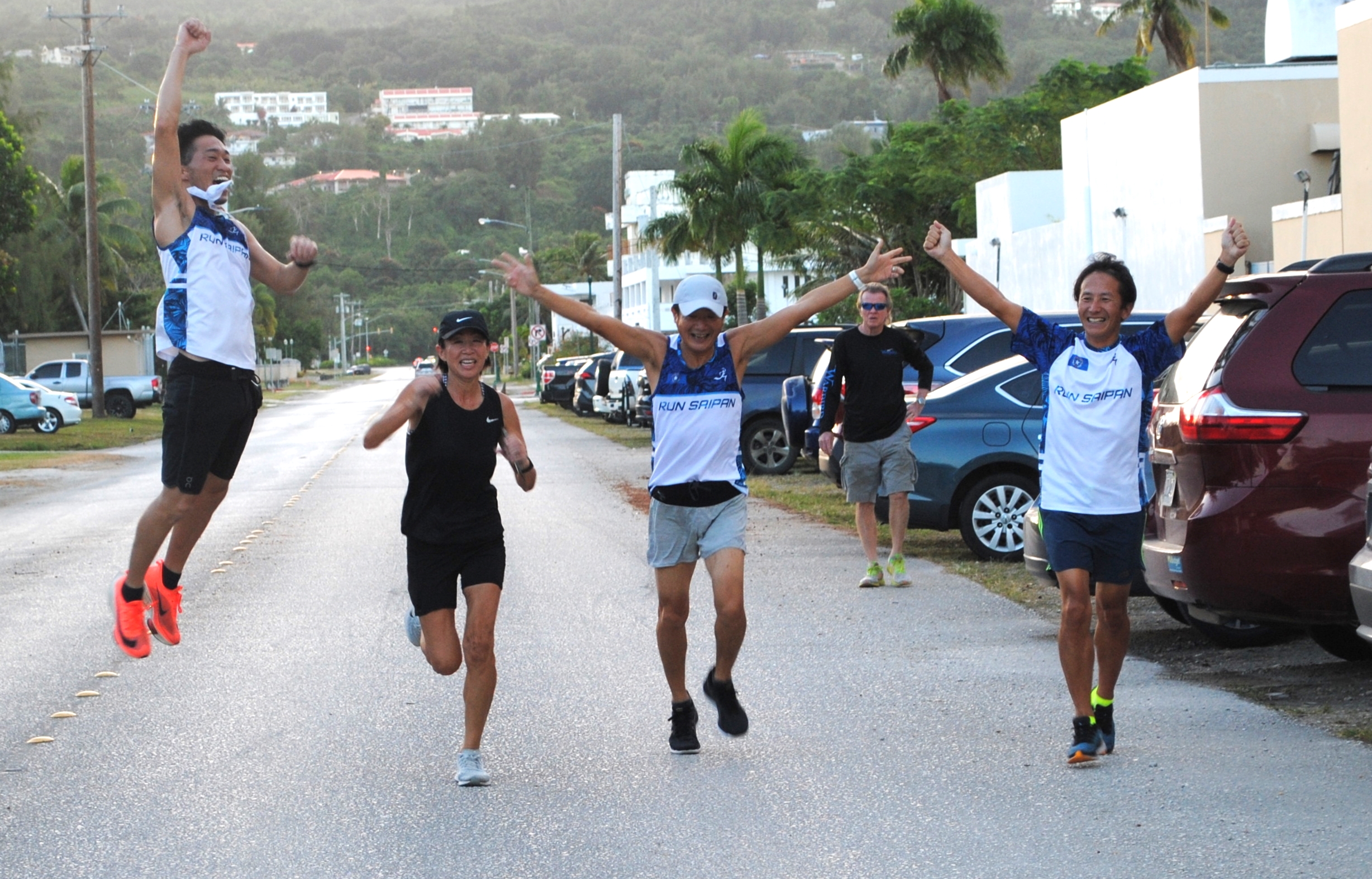 Team KNAS4 members celebrate as they cross the finish line of the Marianas Ekiden at American Memorial Park on Saturday.