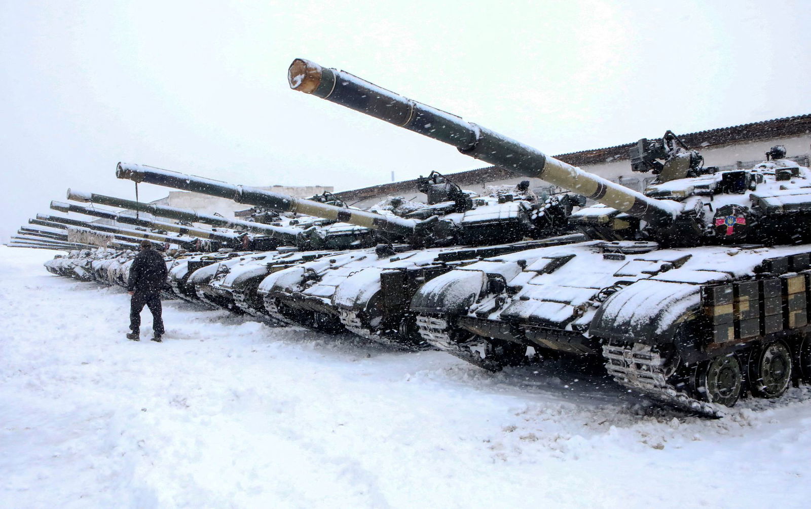 A servicemember walks past tanks of a mechanized brigade of the Ukrainian Armed Forces during military exercises outside Kharkiv, Ukraine, Jan. 31, 2022.