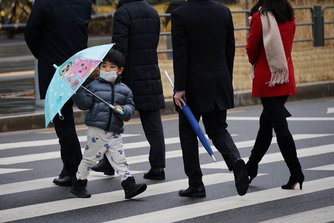A boy wearing a mask to prevent contracting the coronavirus disease walks on a zebra crossing in Seoul, South Korea, Jan. 25, 2022.