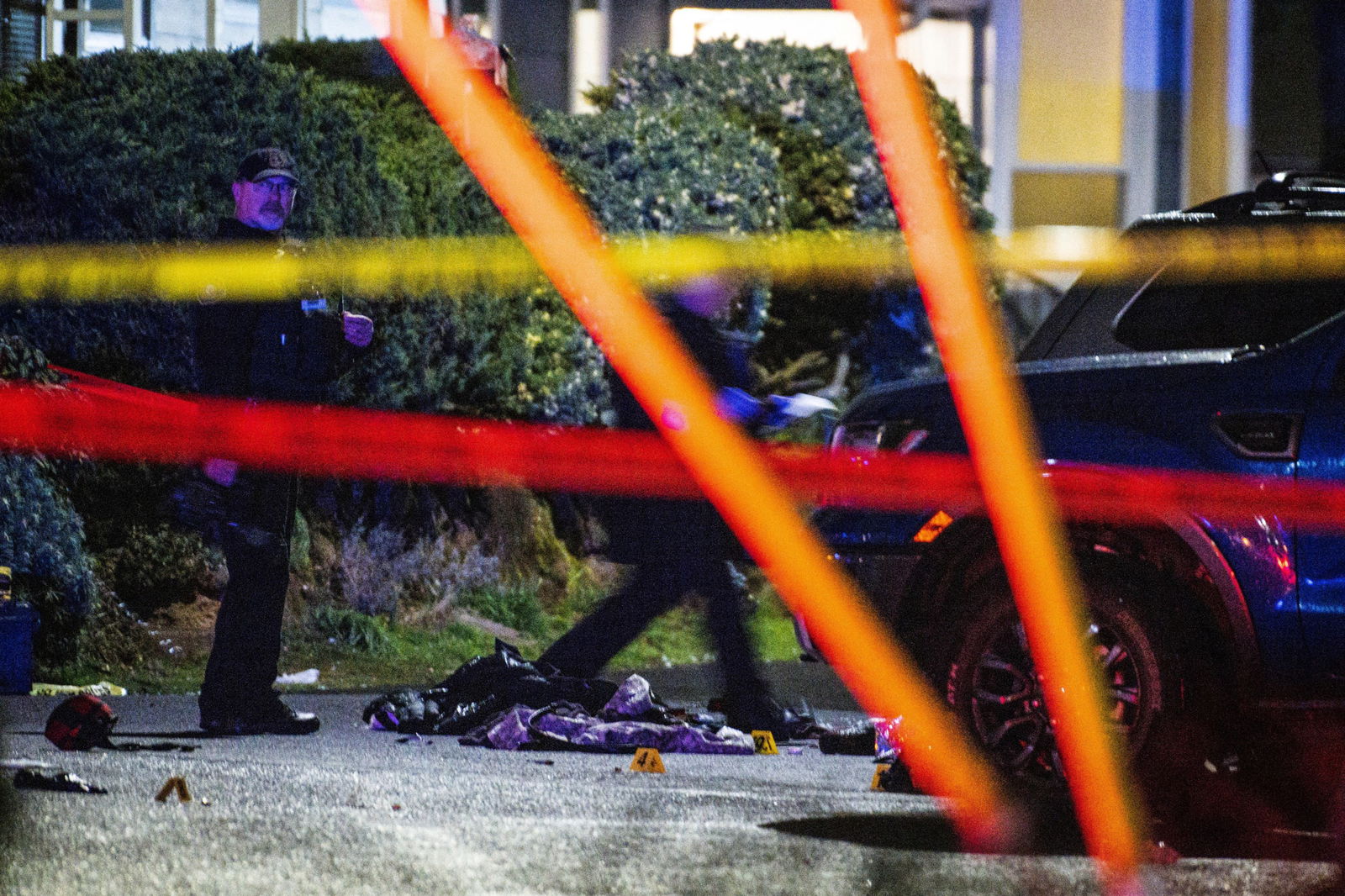 A police officer views the crime scene where one person was shot dead and five others were wounded, at Normandale Park in Portland, Oregon, Feb. 19, 2022.