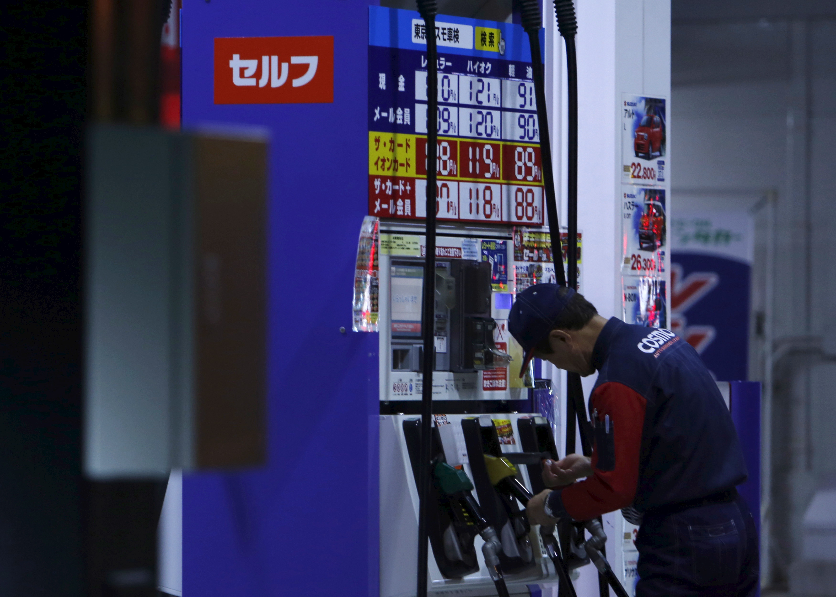 An employee of Cosmo Energy Holdings' Cosmo Oil service station checks its nozzles at a branch in Tokyo, Japan, Dec. 16, 2015.