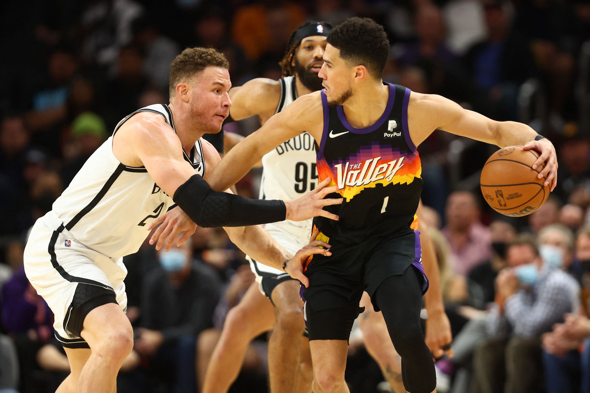 Phoenix Suns guard Devin Booker (1) dribbles the ball around Brooklyn Nets forward Blake Griffin (2) during the second half at Footprint Center. In Phoenix, Arizona on Feb. 1, 2022.