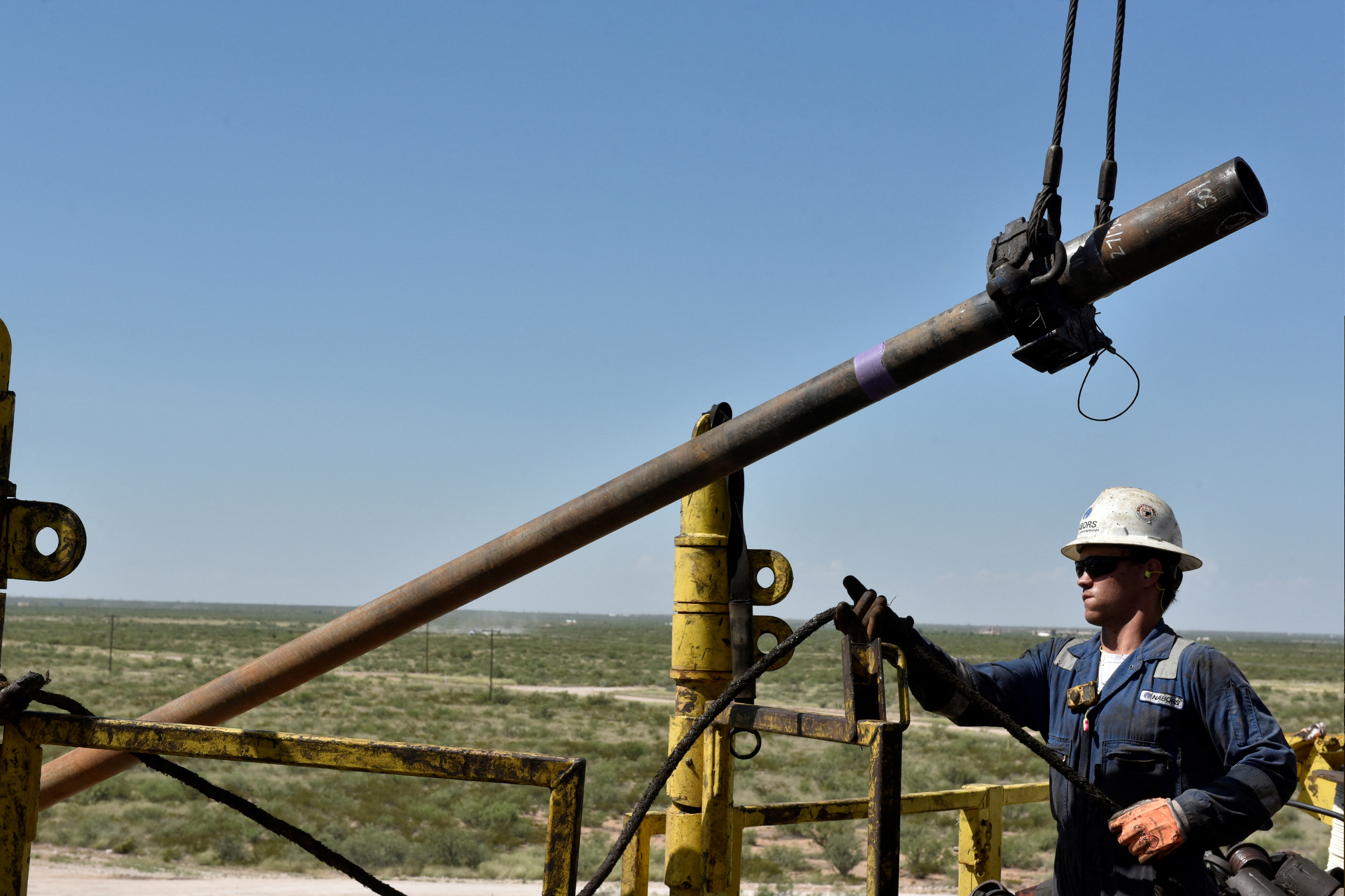 A drilling crew member raises drill pipe onto the drilling rig floor on an oil rig in the Permian Basin near Wink, Texas on Aug. 22, 2018.
