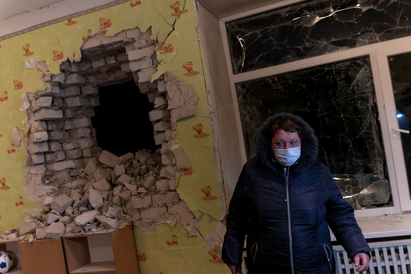 A local resident stands by a hole on the wall inside of a kindergarten classroom, which, according to Ukraine's military officials, was damaged by shelling, in Stanytsia Luhanska, in the Luhansk region, Ukraine, Feb. 17, 2022.