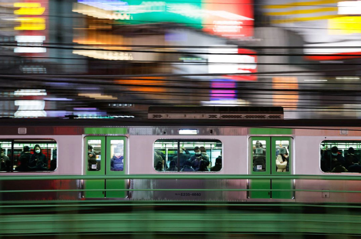 Passengers wearing protective face masks are seen inside a train, amid the coronavirus disease pandemic, in Tokyo, Japan on Feb. 9, 2022. Picture taken with slow shutter speed.