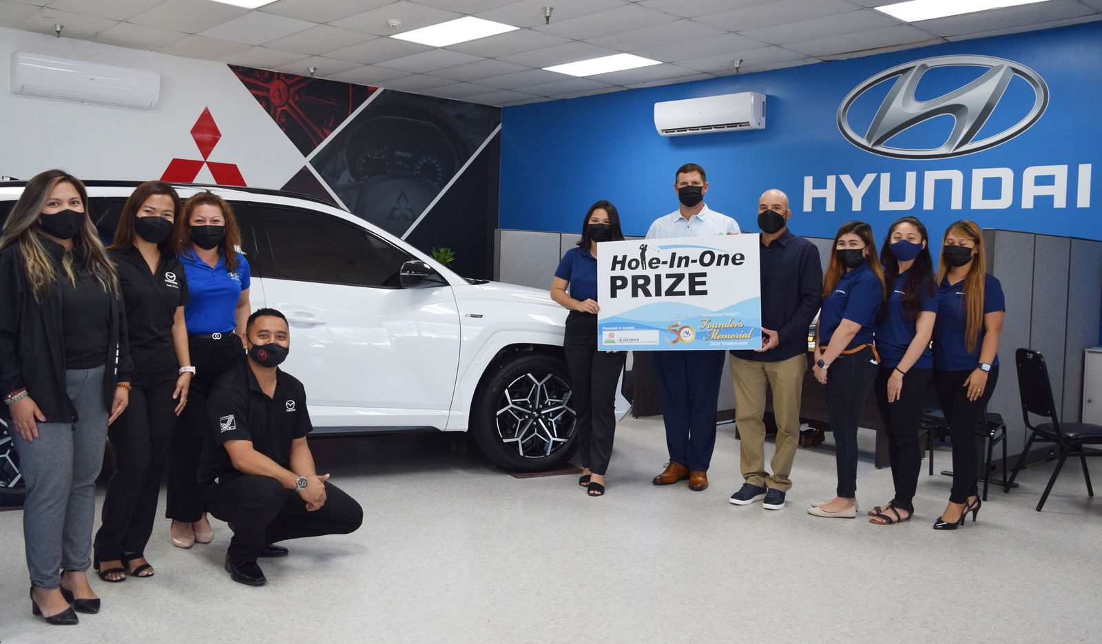 Triple J Motors General Manager Sean Ficke, fifth right, joins Marianas Variety President Amier Younis, fourth right, and MV sales representative Hazel Sadian in holding a ceremonial hole-in-one prize  donated by Triple J Motors to the Marianas Variety Founder's Memorial Golf Tournament set for Saturday, April 2 at 6 a.m., LaoLao Bay Golf & Resort, West Course. Also in photo are Triple J sales representative Jamie Barcinas, sales manager Jasmine Matsumoto, sales representatives Julie Ogo and Brandon Santos with MV sales representatives Gwendolyn Sandig, Monique Mascarinas and Dianne Lumapas.