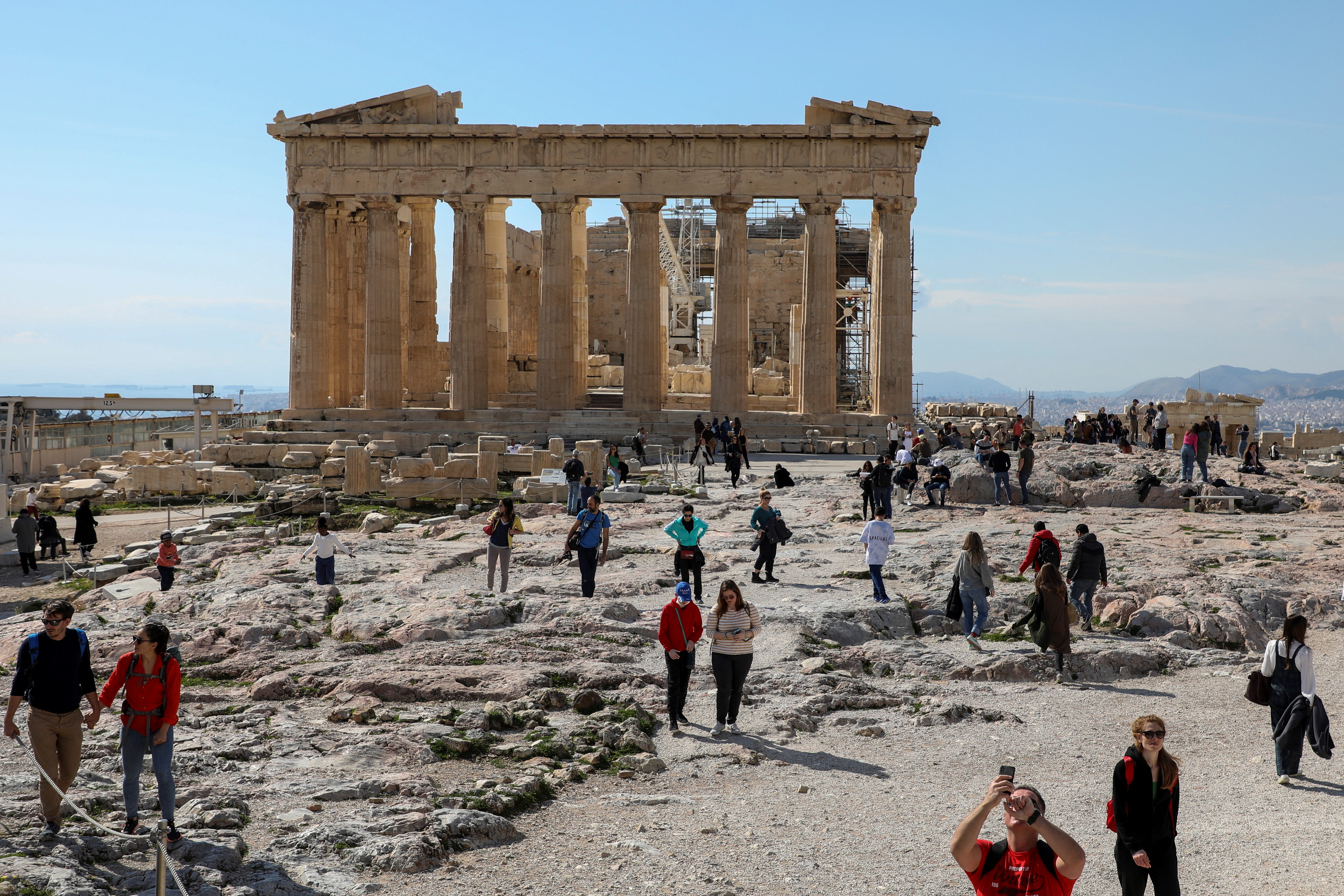People visit the ancient Parthenon Temple atop the Acropolis hill archaeological site in Athens, Greece, Feb. 26, 2022.