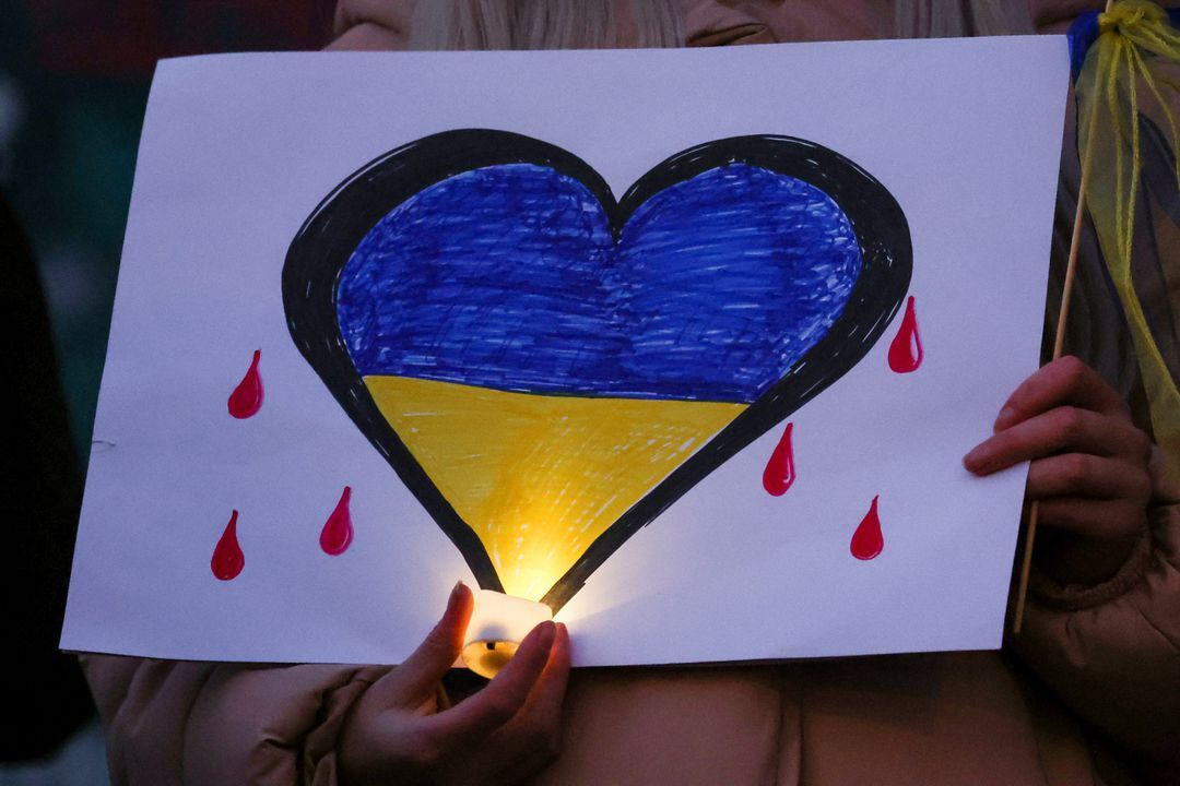 A person holds a candle and a poster during a vigil held in support of Ukraine, following Russia's invasion of Ukraine, in Liverpool, Britain, March 1, 2022.