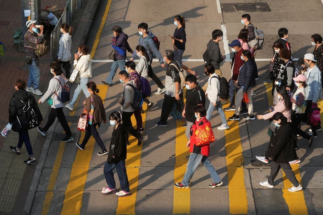 People wearing face masks cross a street following the coronavirus disease outbreak, in Hong Kong, Feb. 15, 2022.