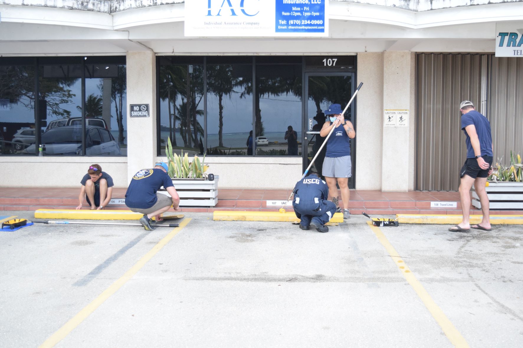 U.S. Coast Guard Cutter Oliver Henry crewmembers paint the parking stops at the CDA building on Beach Road in San Jose Saturday.