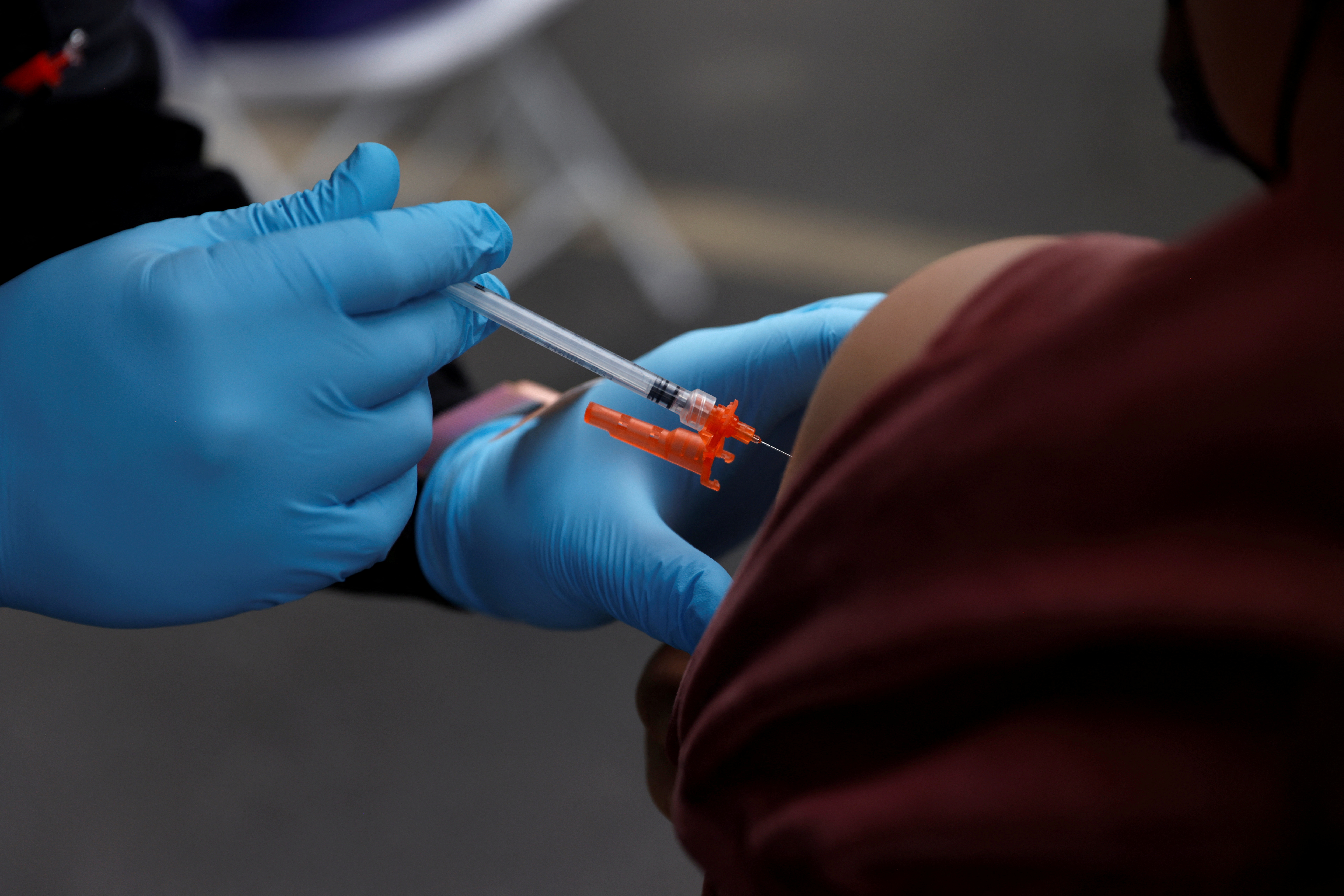 A healthcare worker administers  the second dose of the Pfizer-BioNTech coronavirus disease vaccine to a person at the L.A. Care Health Plan free testing and vaccination site at the First African Episcopal Church in Los Angeles, California, Jan. 29, 2022.