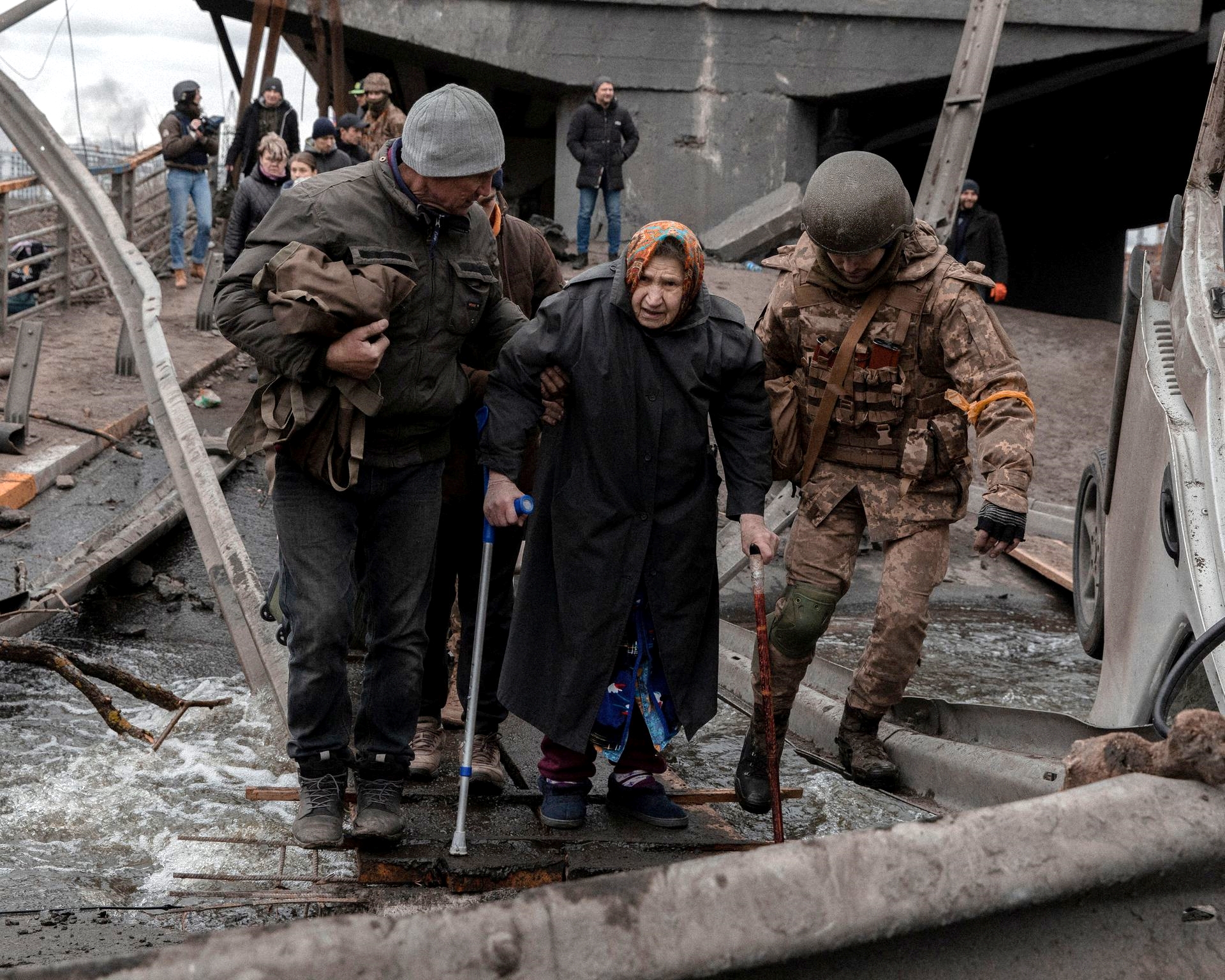 An elderly woman is helped while crossing a destroyed bridge as she tries to leave the city of Irpin, in the Kyiv region, Ukraine on March 5, 2022.