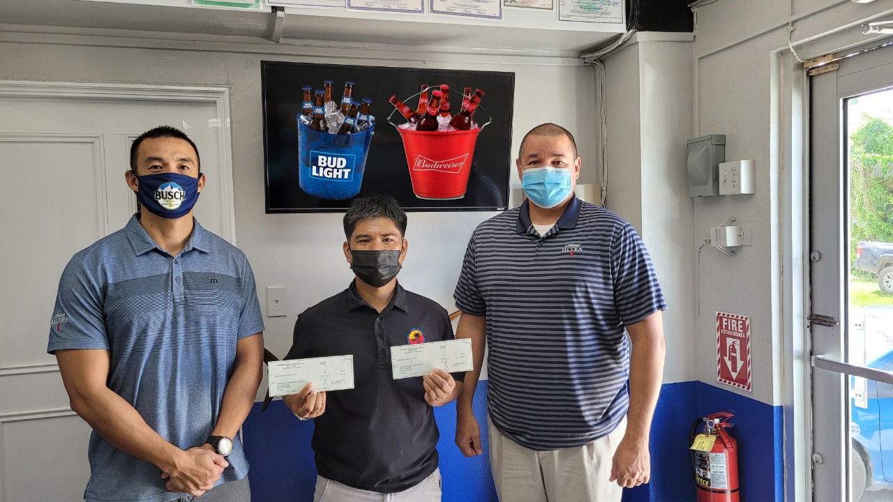 Warlee T. Ellama, secretary of the Saipan Electronic Darts Association and the Saipan Billiards Association, holds the sponsorship checks handed by Marpac General Manager Guy Pudney and Sales Manager James Lee.