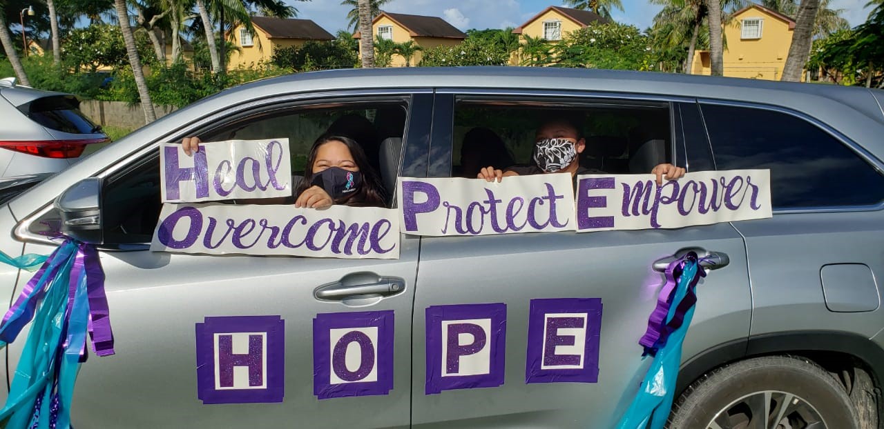 Community members pose for a photo at the 2020 Driving Out Domestic Violence Motorcade displaying the 2020 Domestic Violence Awareness Month theme for the CNMI, H.O.P.E. (Heal. Overcome. Protect. Empower.) 