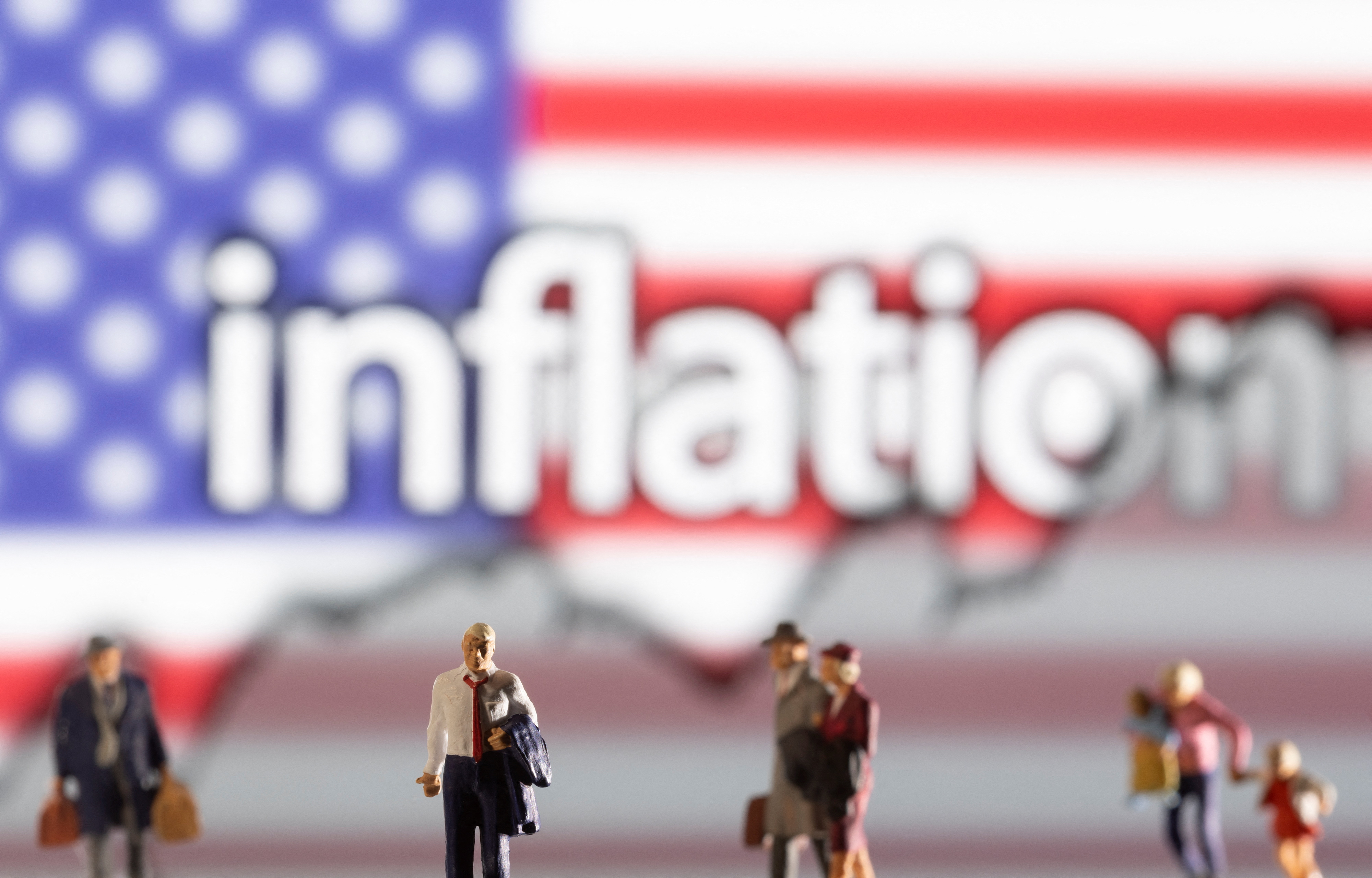 Small figurines are seen in front of displayed word "Inflation," U.S. flag and rising stock graph in this illustration taken Feb. 11, 2022.