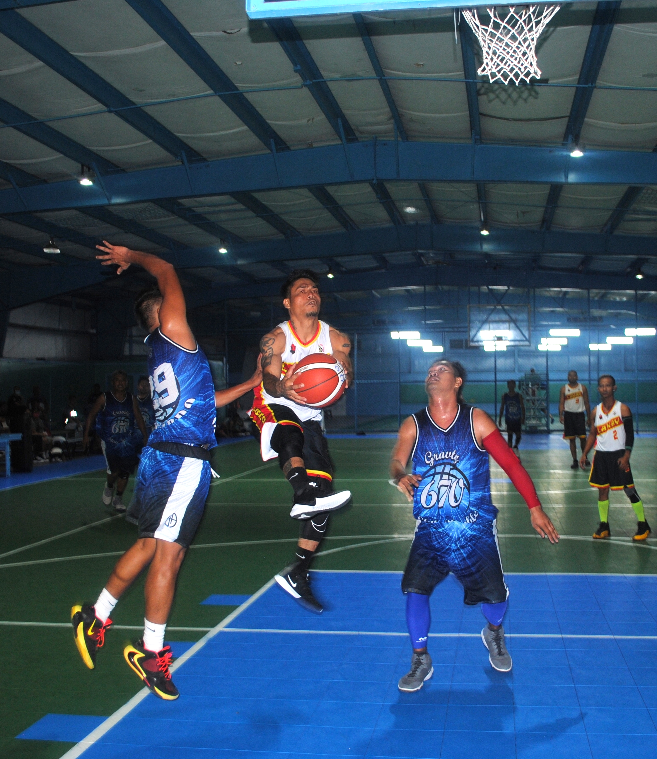 Lakay's Palacios goes up for the shot against two defenders during an Open Division game of the Saipan Centennial Lions Club Basketball League at the TSL Sports Complex on Saturday.
