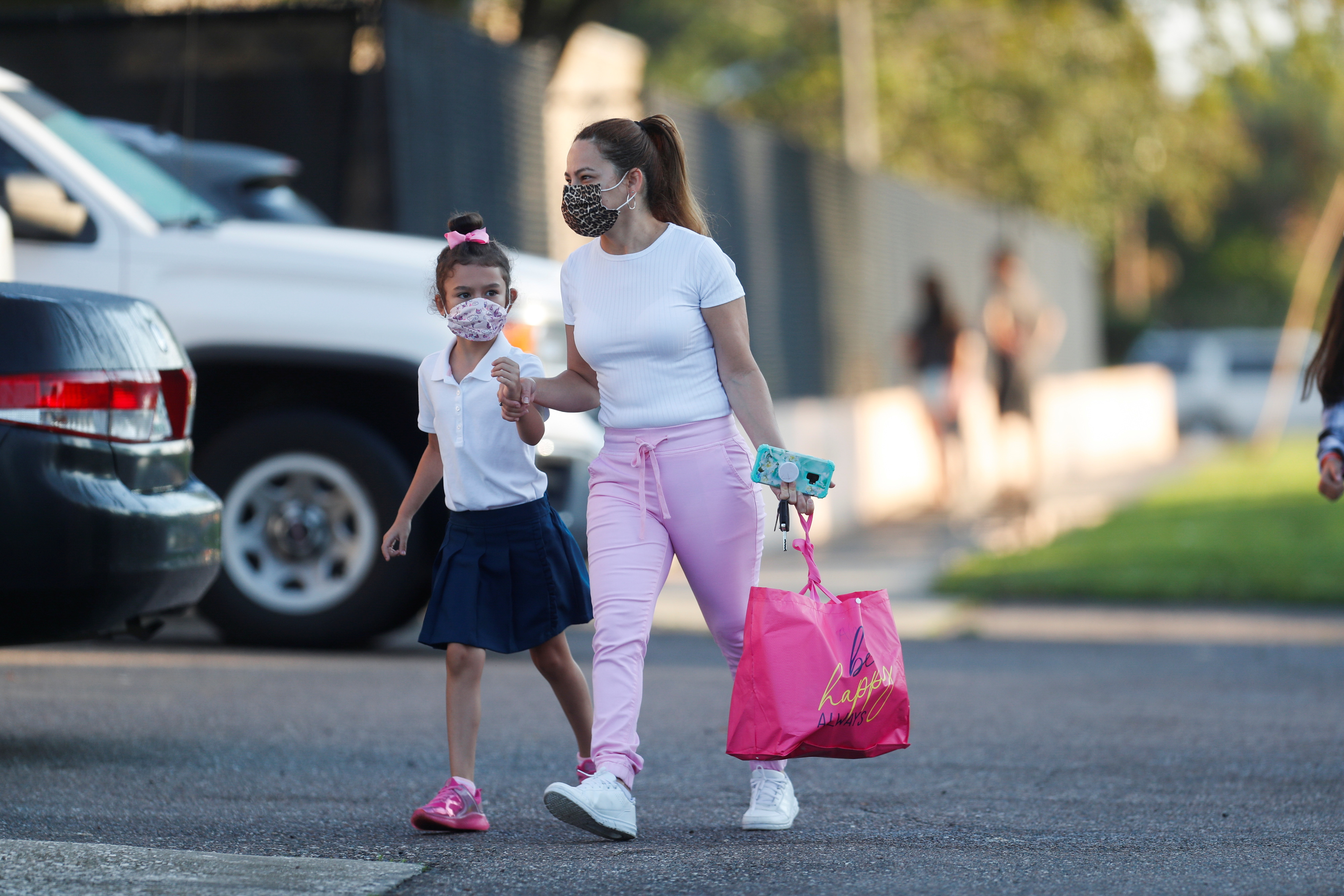 A mother walks her daughter on the first day of school, amid the coronavirus pandemic, at West Tampa Elementary School in Tampa, Florida, Aug. 10, 2021.